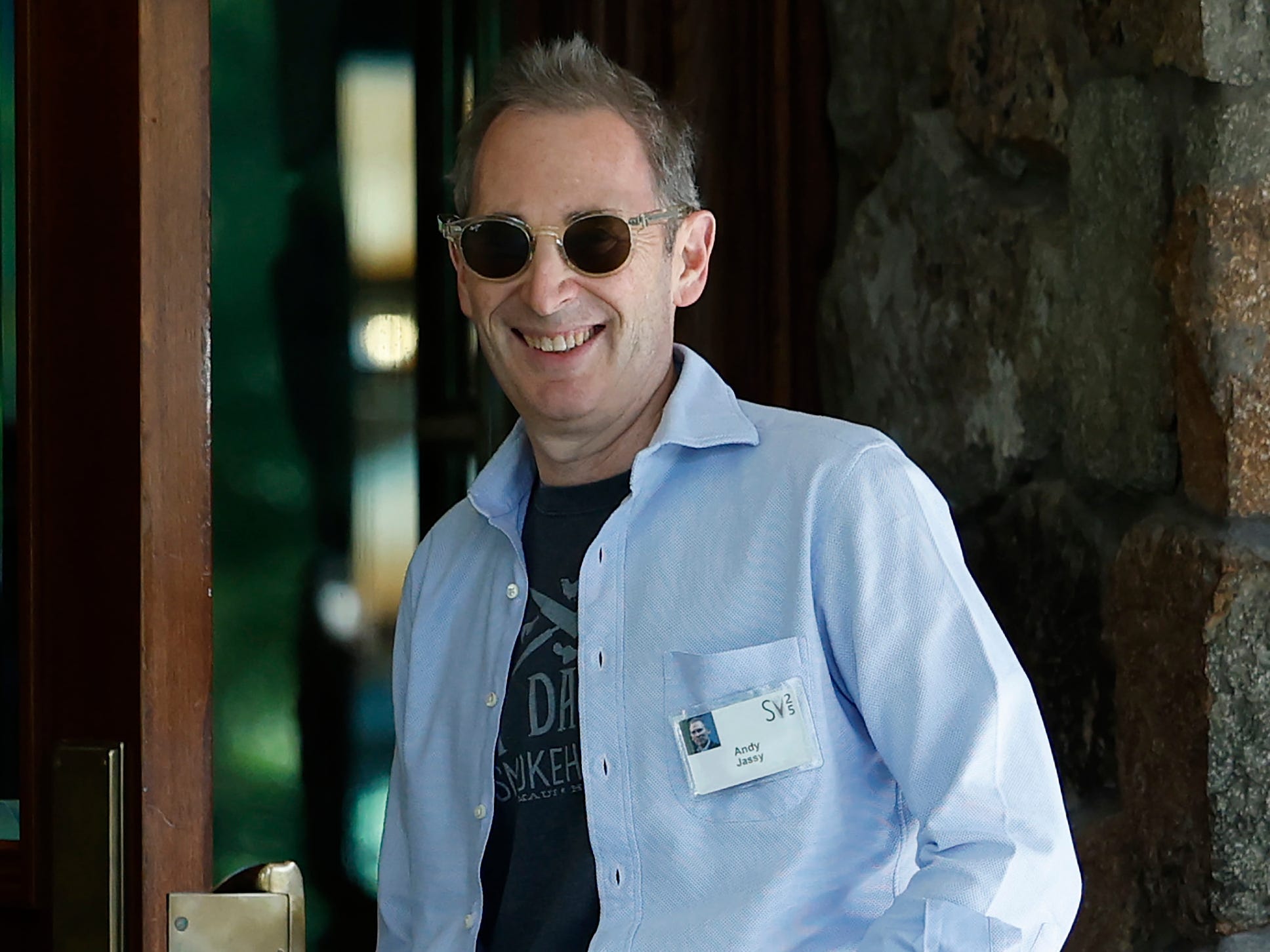 Andy Jassy smiling and wearing a blue shirt and jeans at the Sun Valley conference.