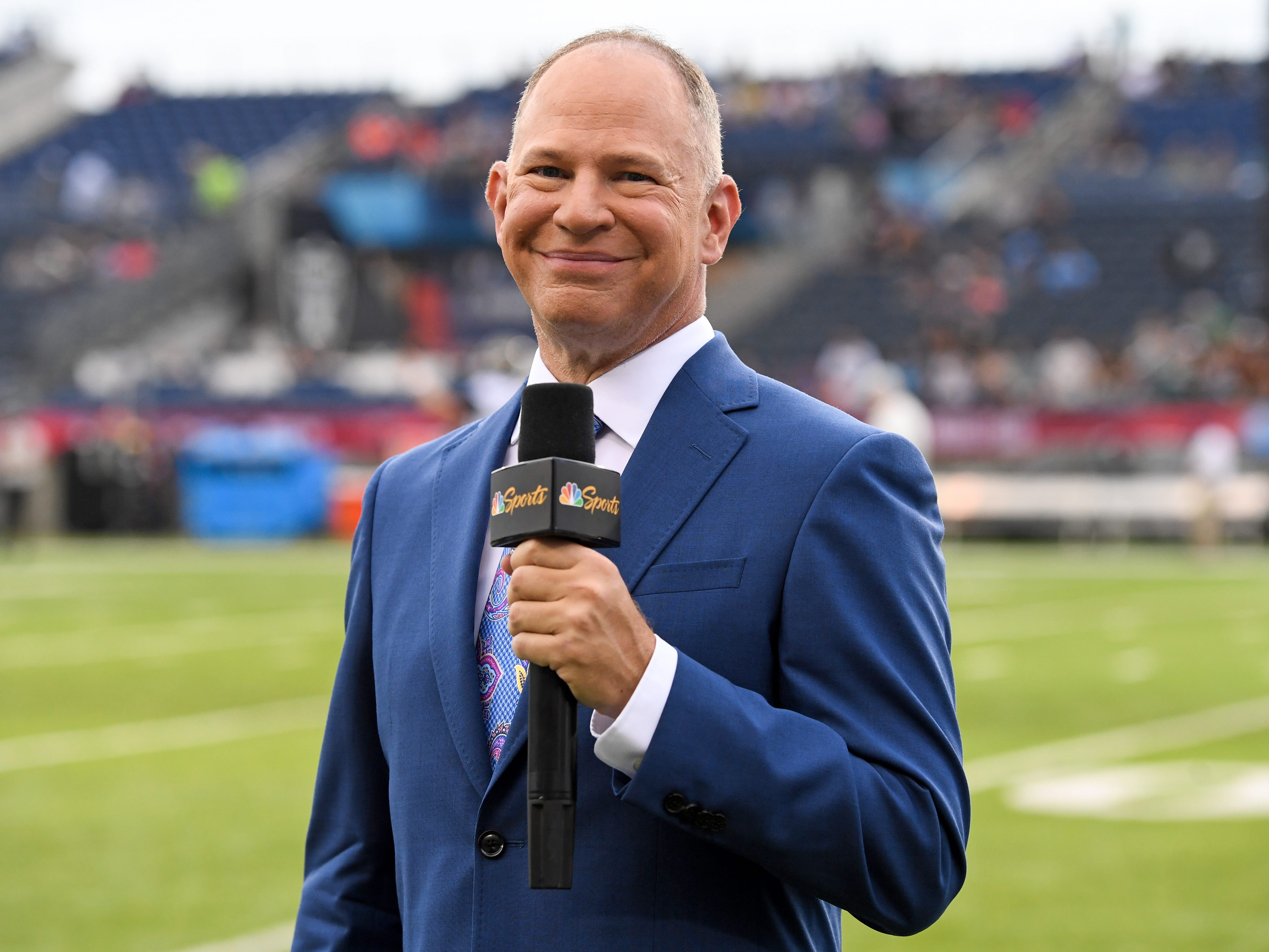 Matthew Berry holding a NBC sports microphone at a game.