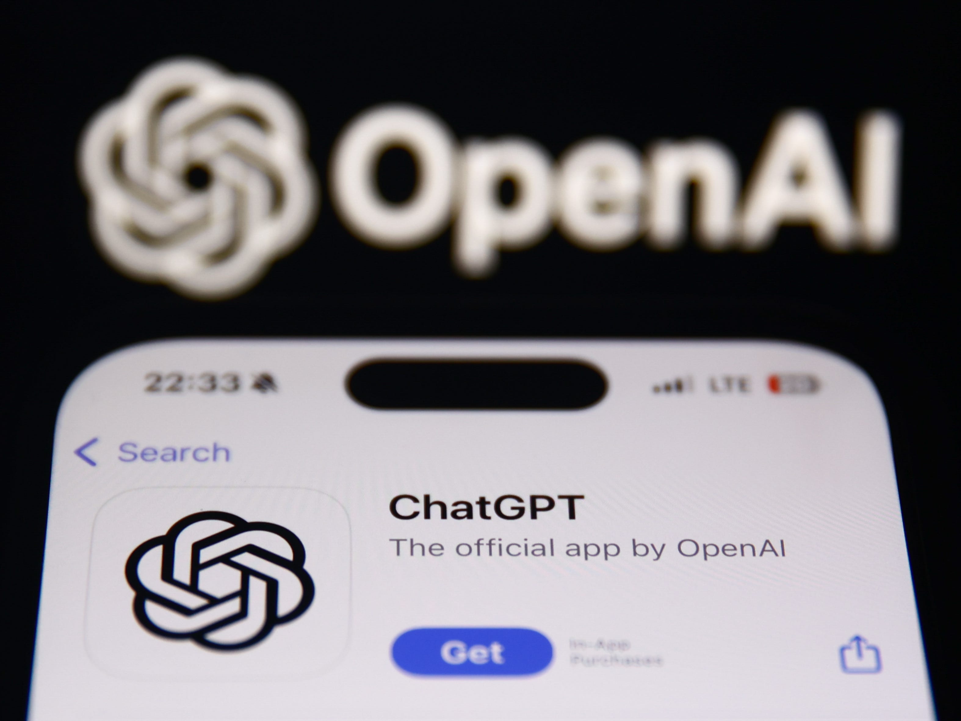 The ChatGPT page on Apple's App Store being displayed on a phone screen in front of the OpenAI logo.