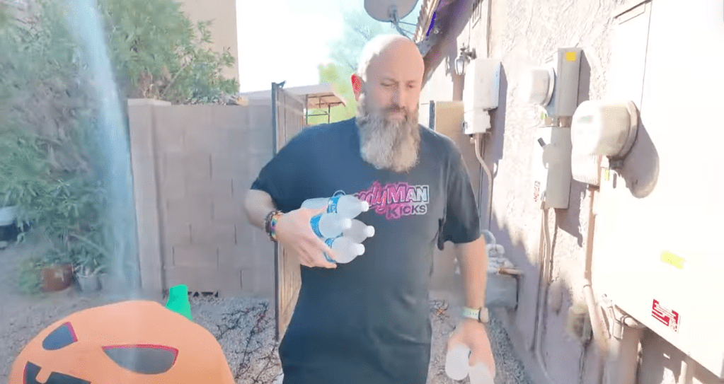 David Martin carries water bottles in his yard to a cooler set up in his driveway in Goodyear, Arizona.