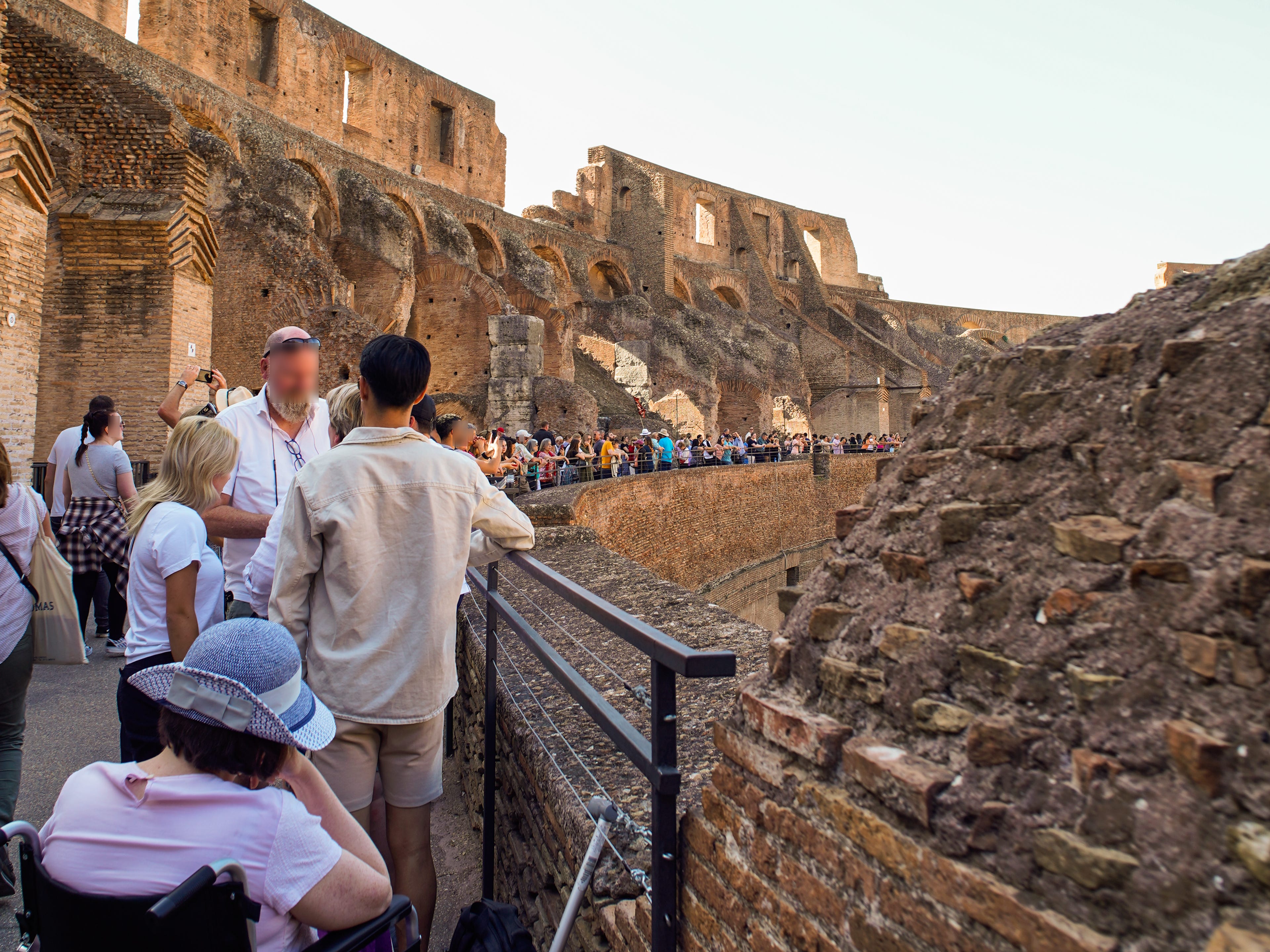 Crowds of people stand on the edge of the Colosseum in Rome