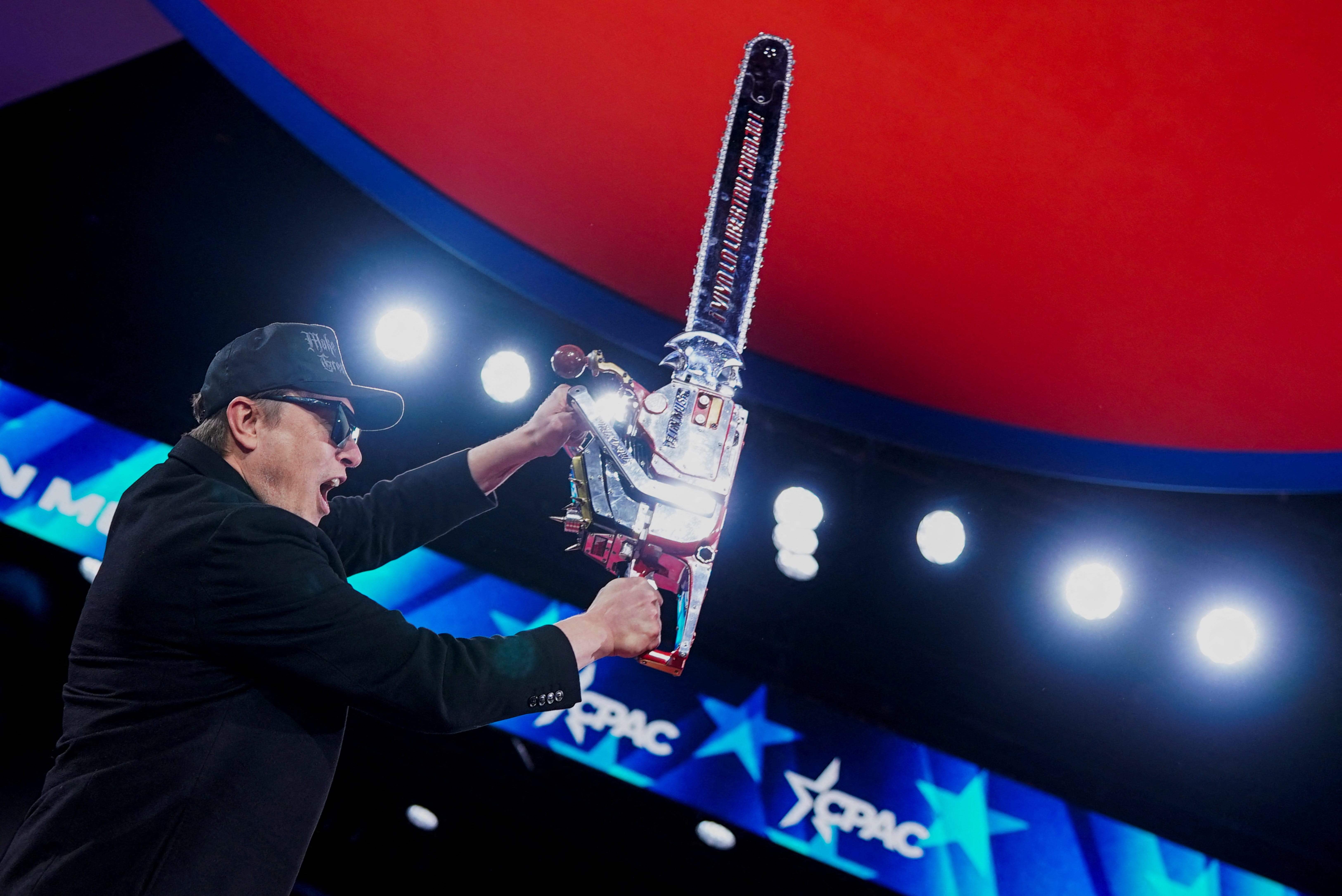 Elon Musk holds up a chainsaw onstage during the Conservative Political Action Conference (CPAC) in National Harbor, Maryland, U.S
