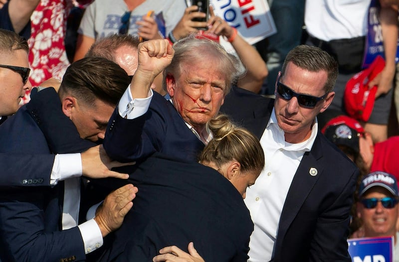 Republican candidate Donald Trump is seen with blood on his face surrounded by secret service agents on July 13, 2024.