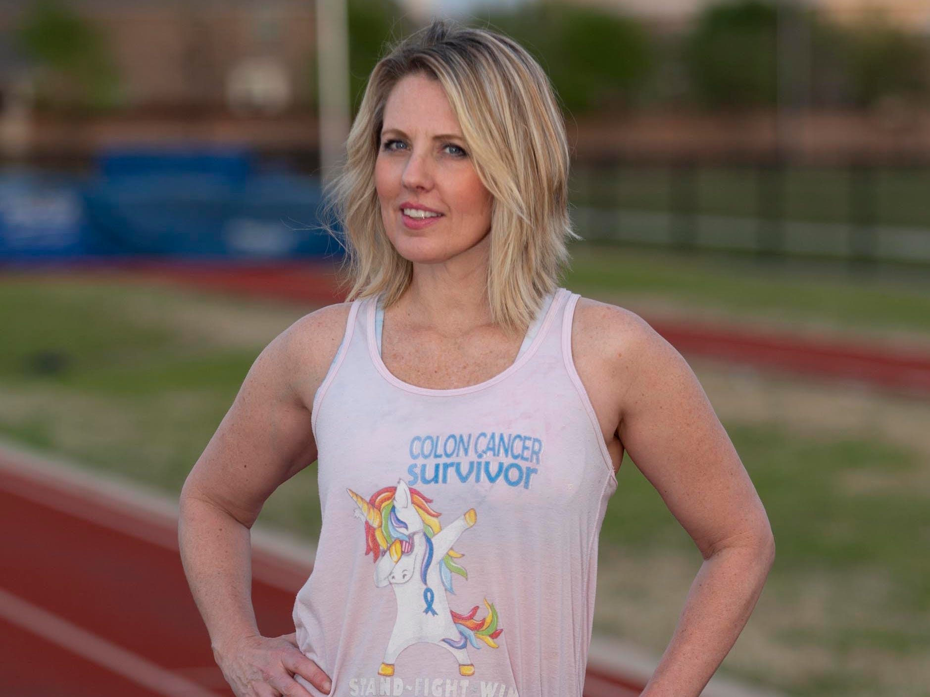 Tracy Robert wearing a colon cancer survivor shirt and standing on a track