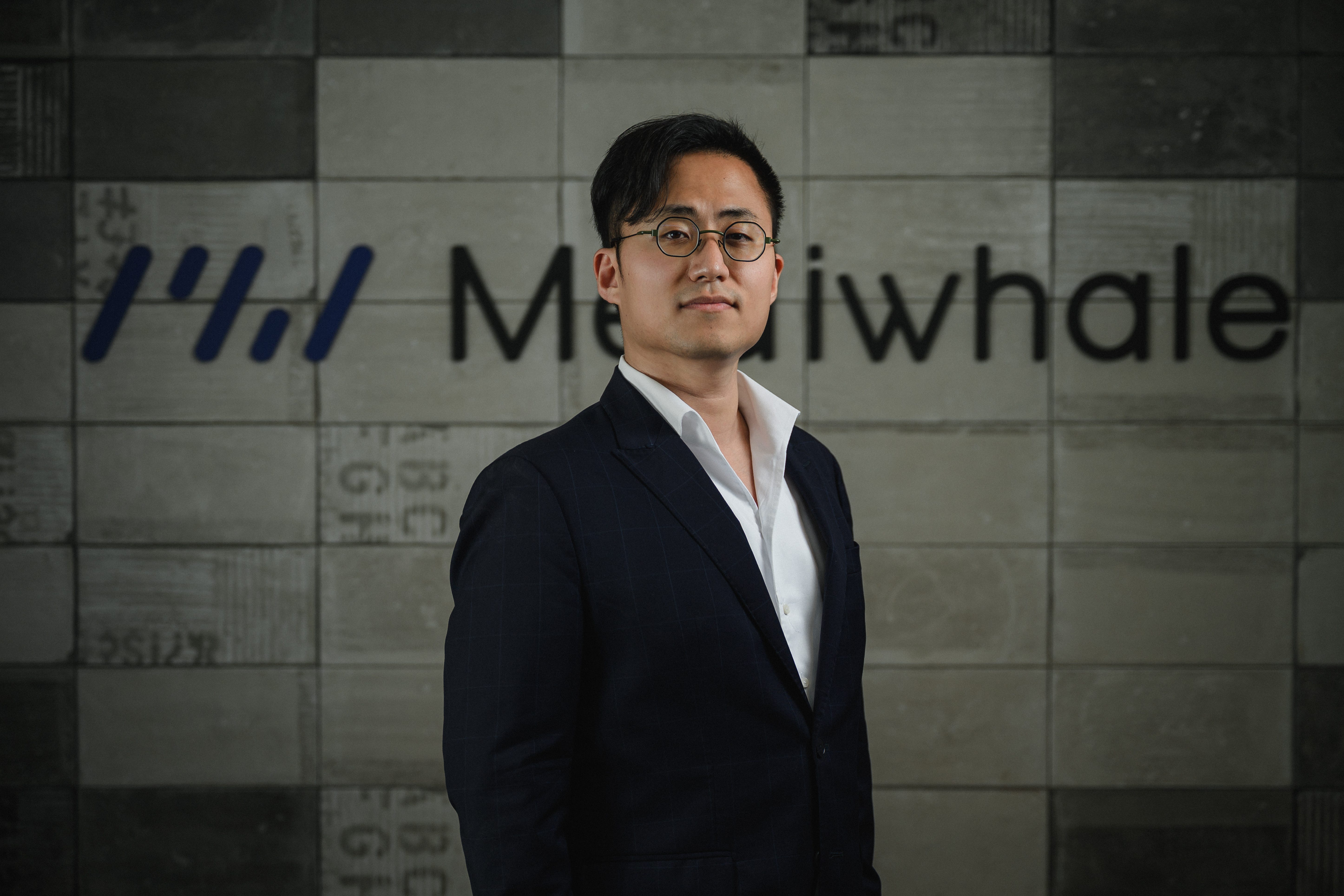 Kevin Choi stands in front of the logo Mediwhale