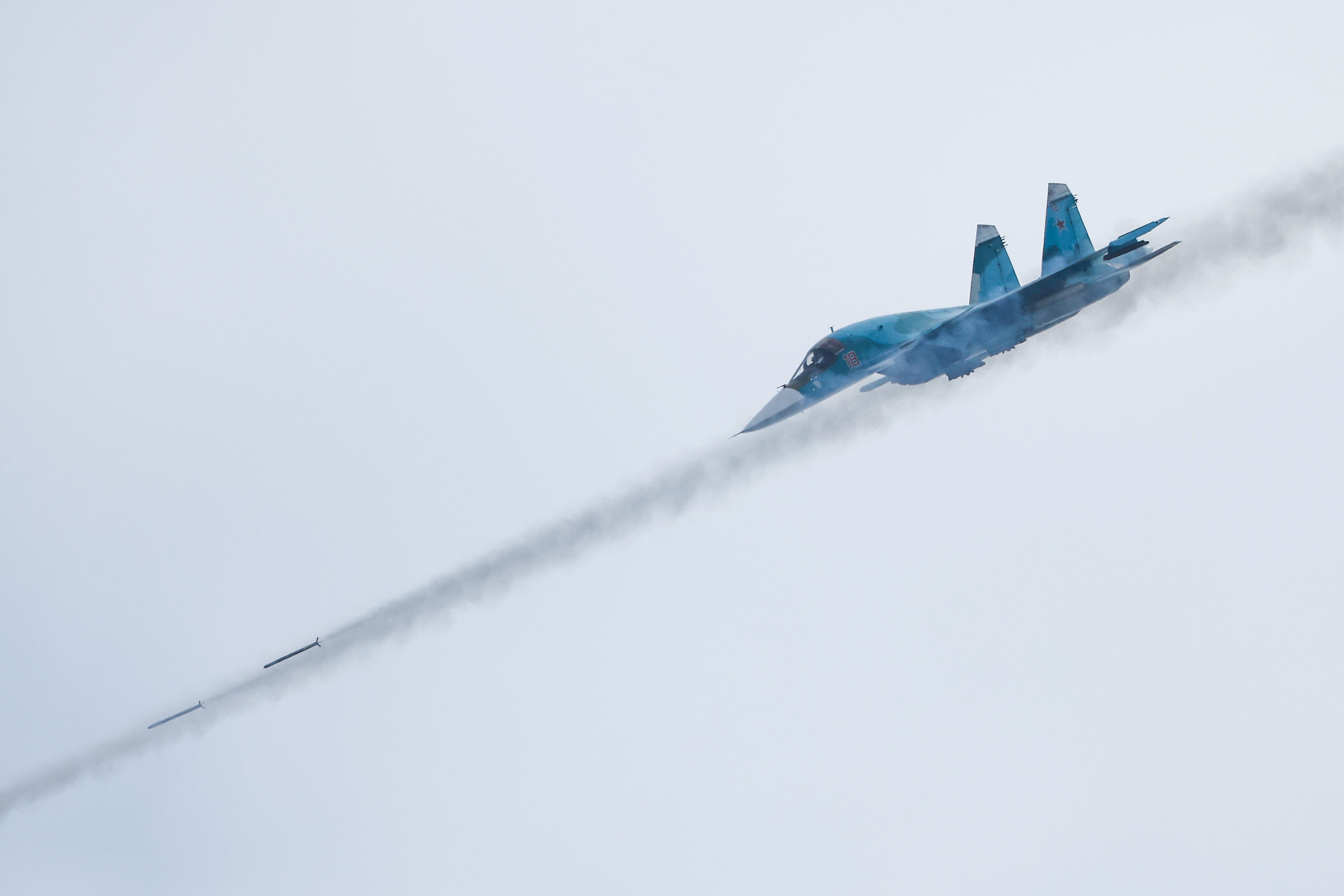 A fighter-bomber aircraft flying downward and firing missiles.