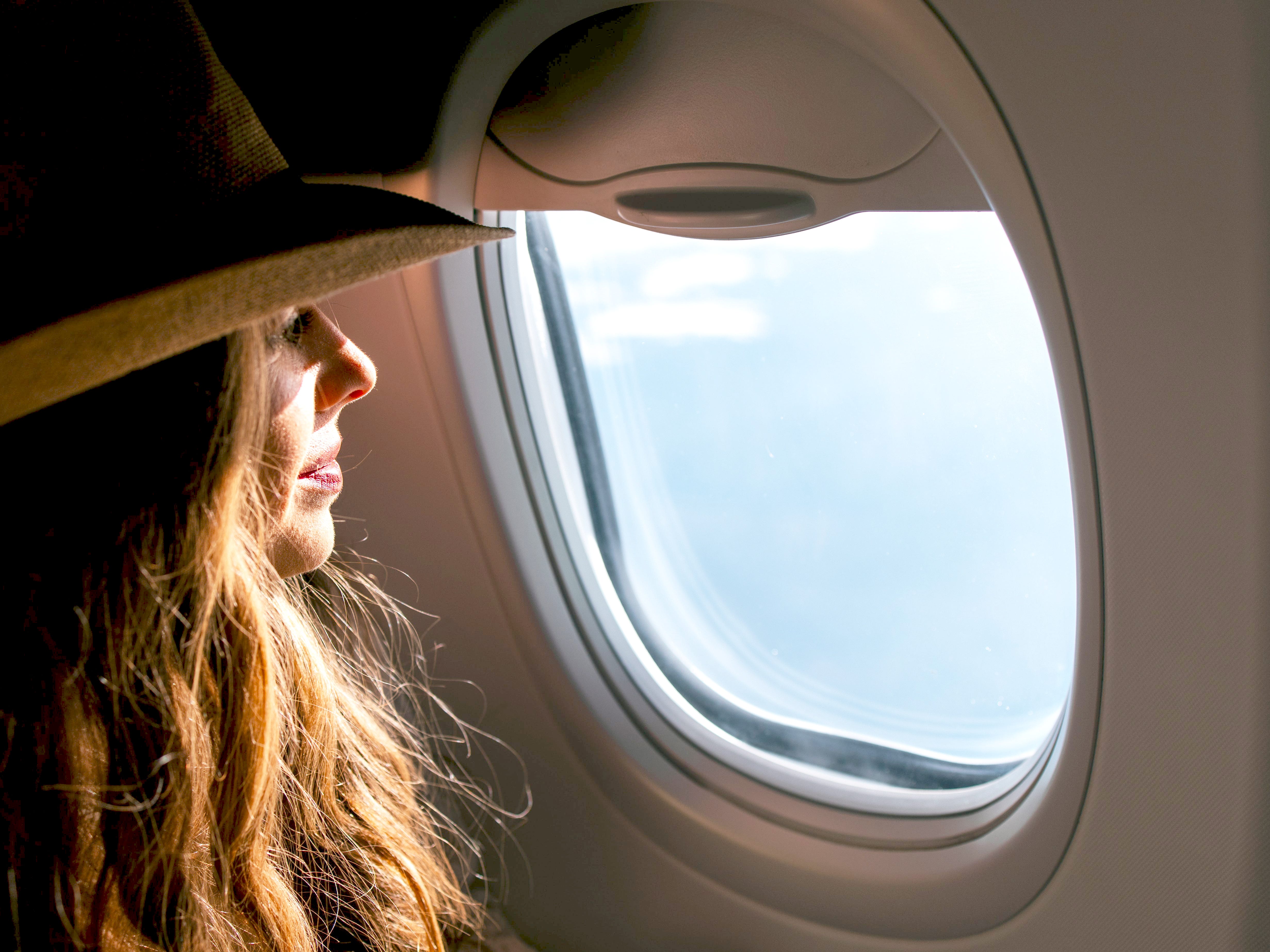 A woman sits on a plane and looks out the window.