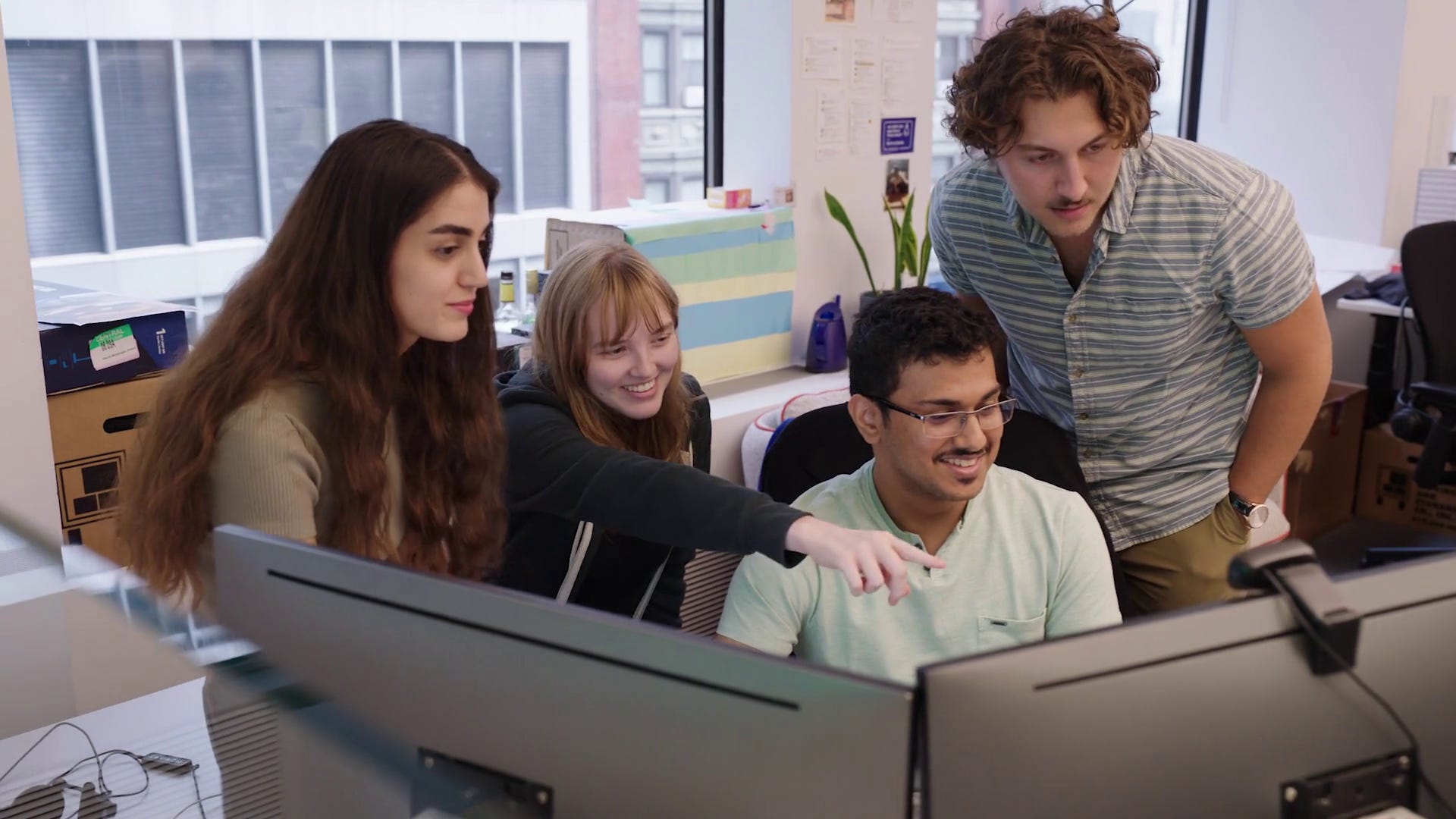 Four D. E. Shaw interns gathered around a computer.