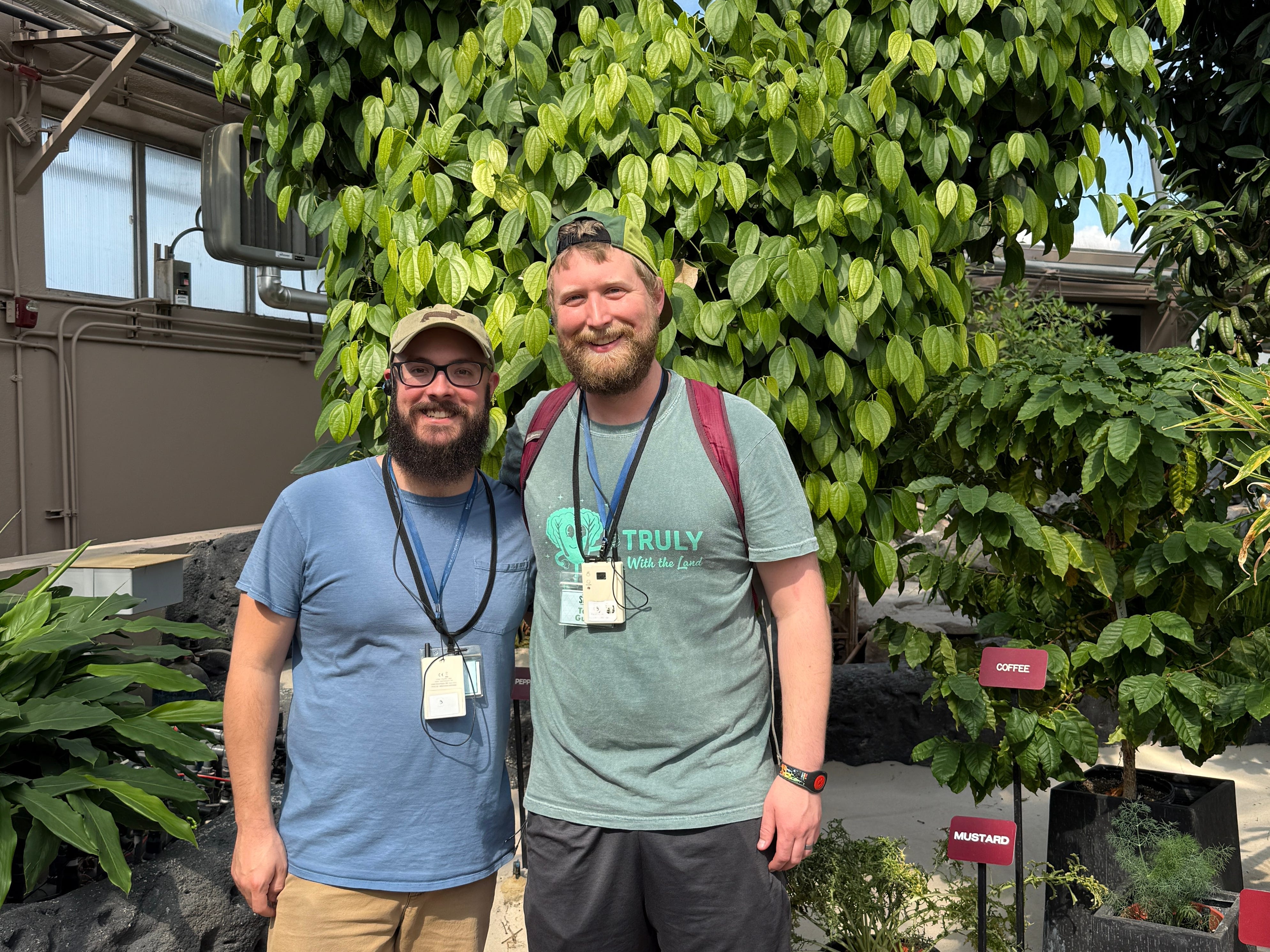 Author Timothy Moore and his husband smiling in front of plant on Behind the Seeds Tour in Disney