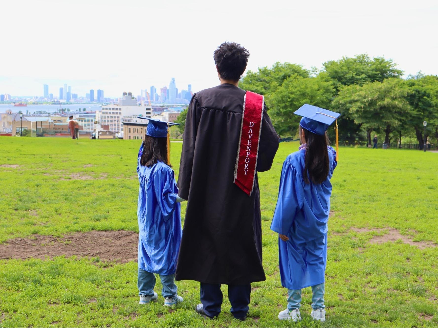 Brian Zhang with two young kids all in graduation gowns looking at the skyline