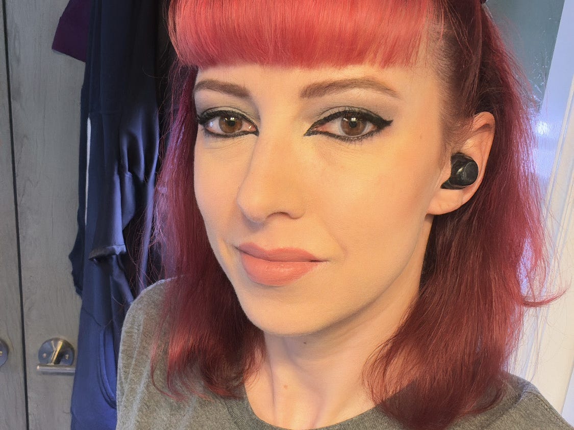 a woman with pink hair and heavy eye makeup taking a selfie indoors
