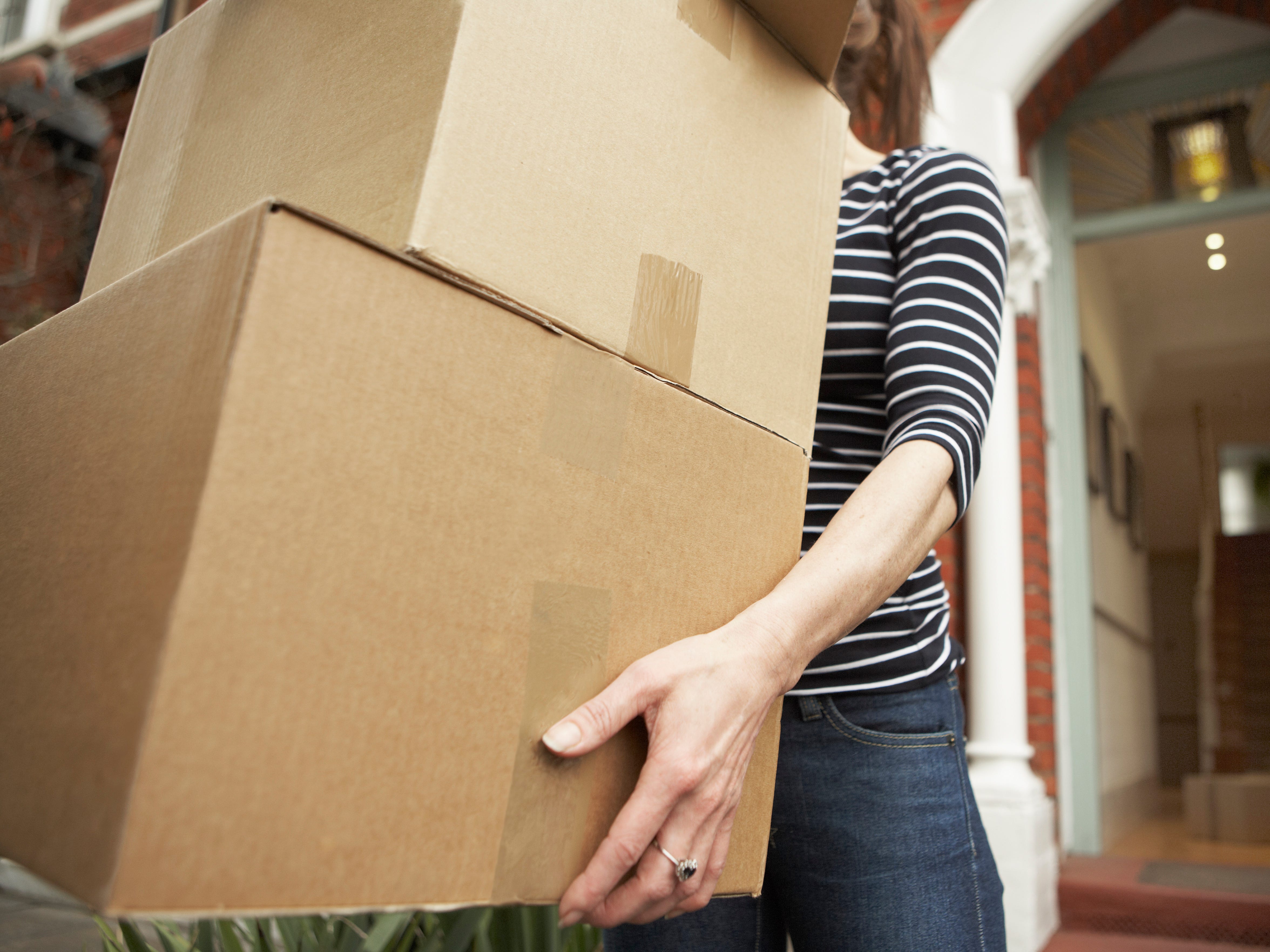 woman carrying cardboard boxes, wearing stripes black and white shirt