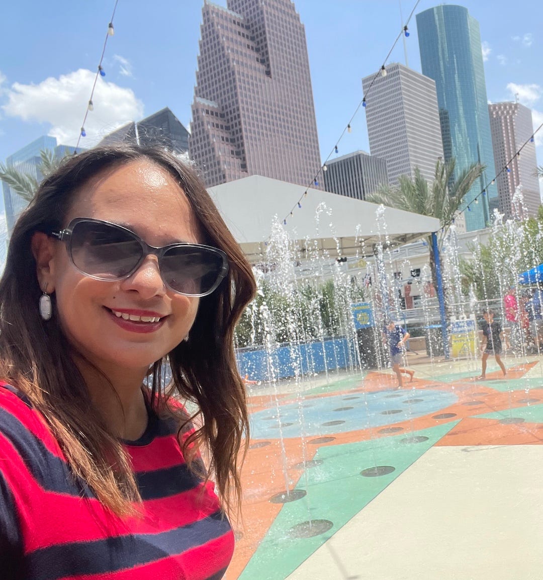 woman in sunglasses and striped red shirt takes selfie in downtown Houston
