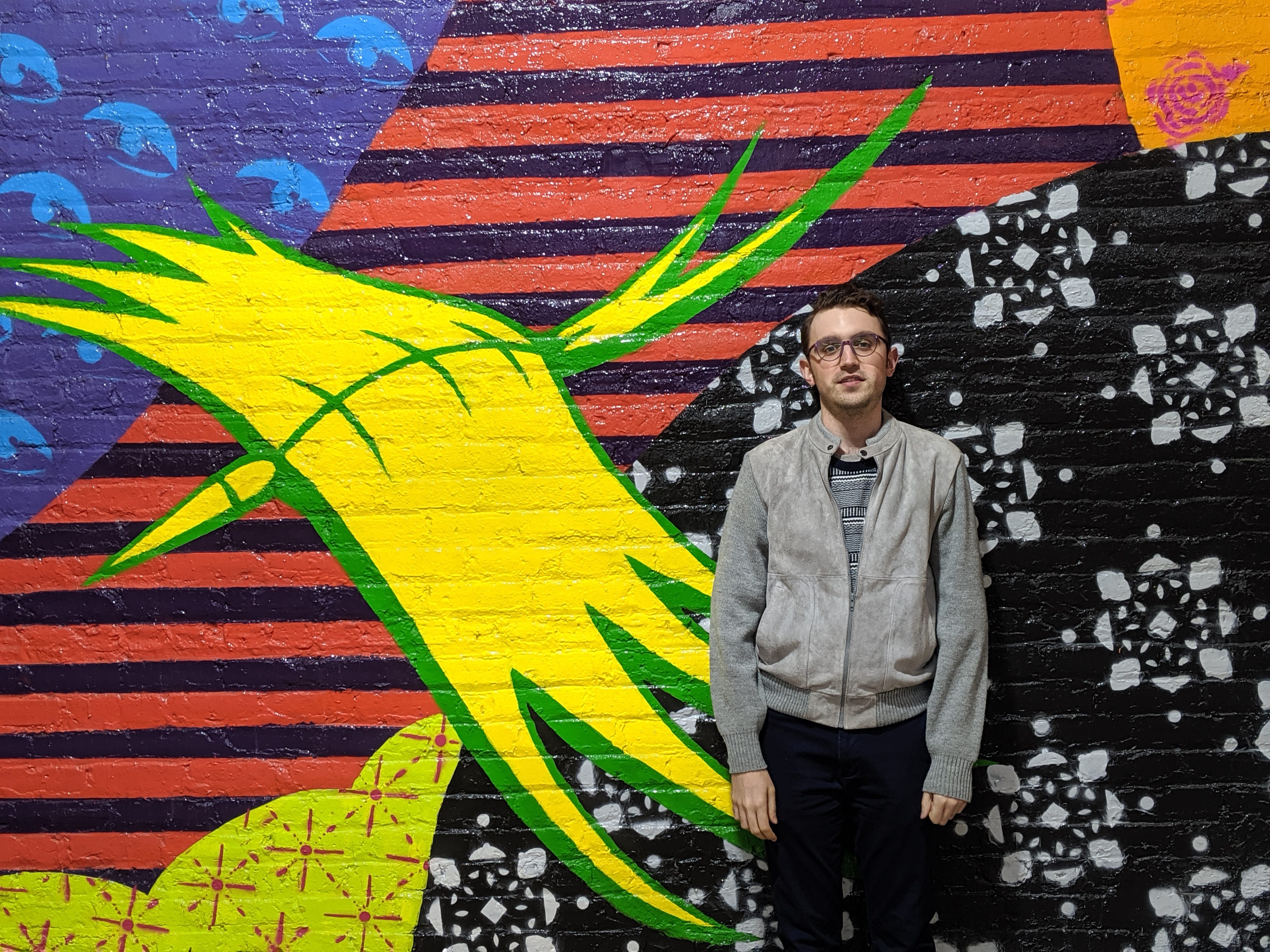a man standing net to a colorful mural
