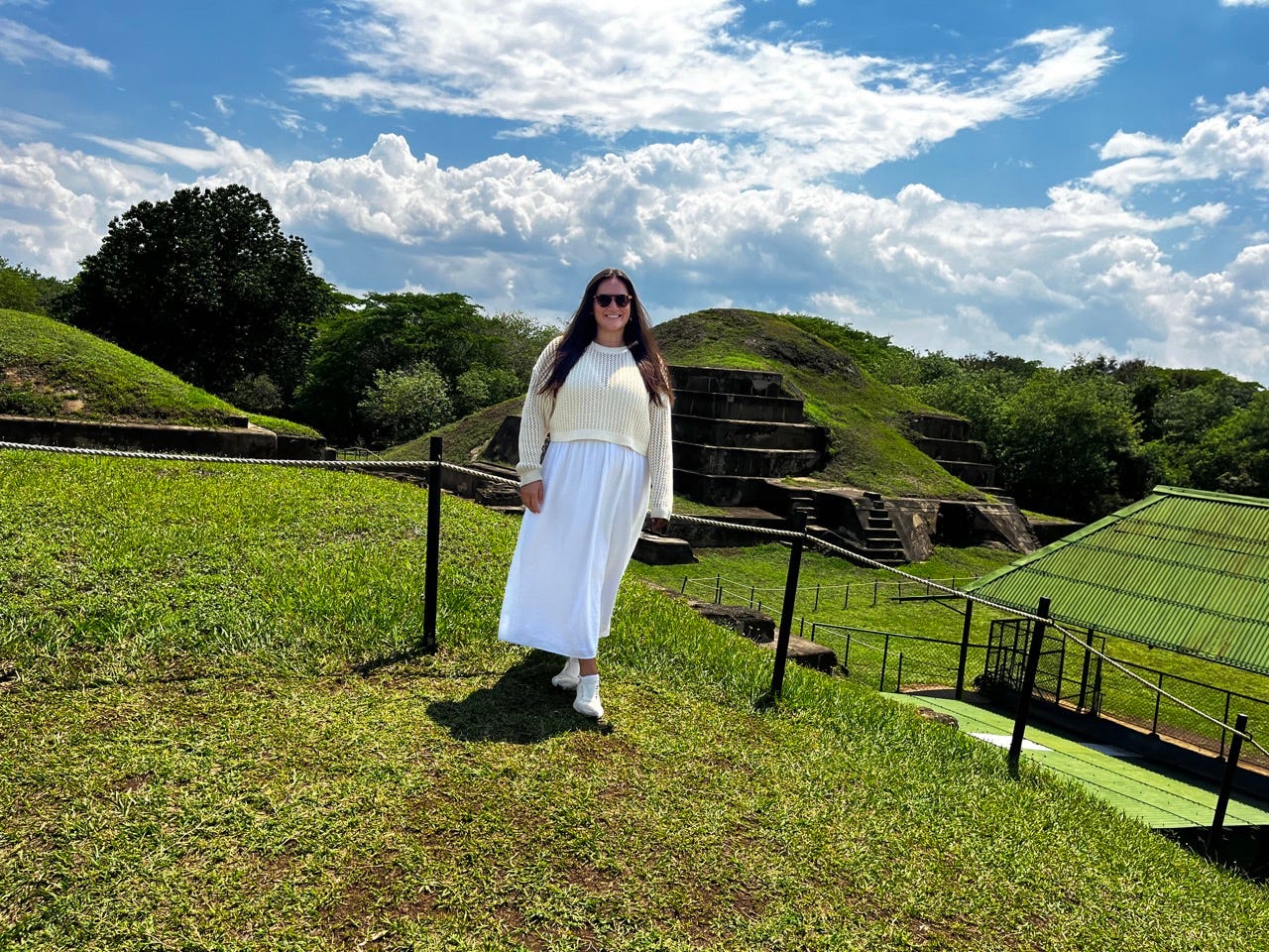 Author Lola Méndez smiling in front of green-covered pyramid structure