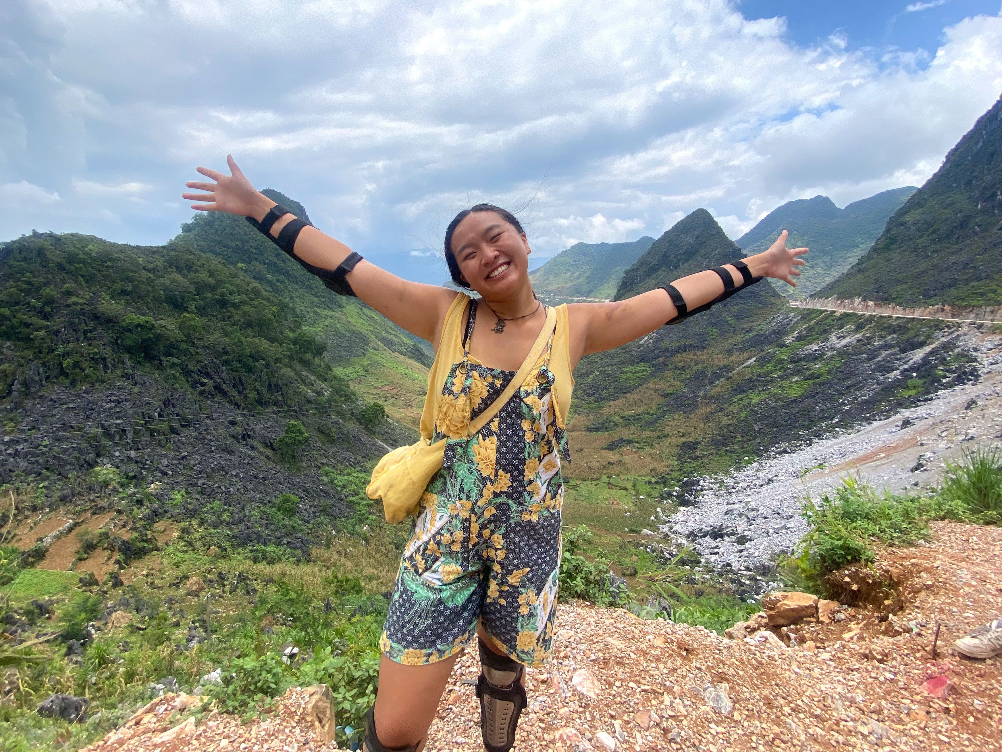 Christina stretches her arms out to the side while posing in the mountains in Vietnam.