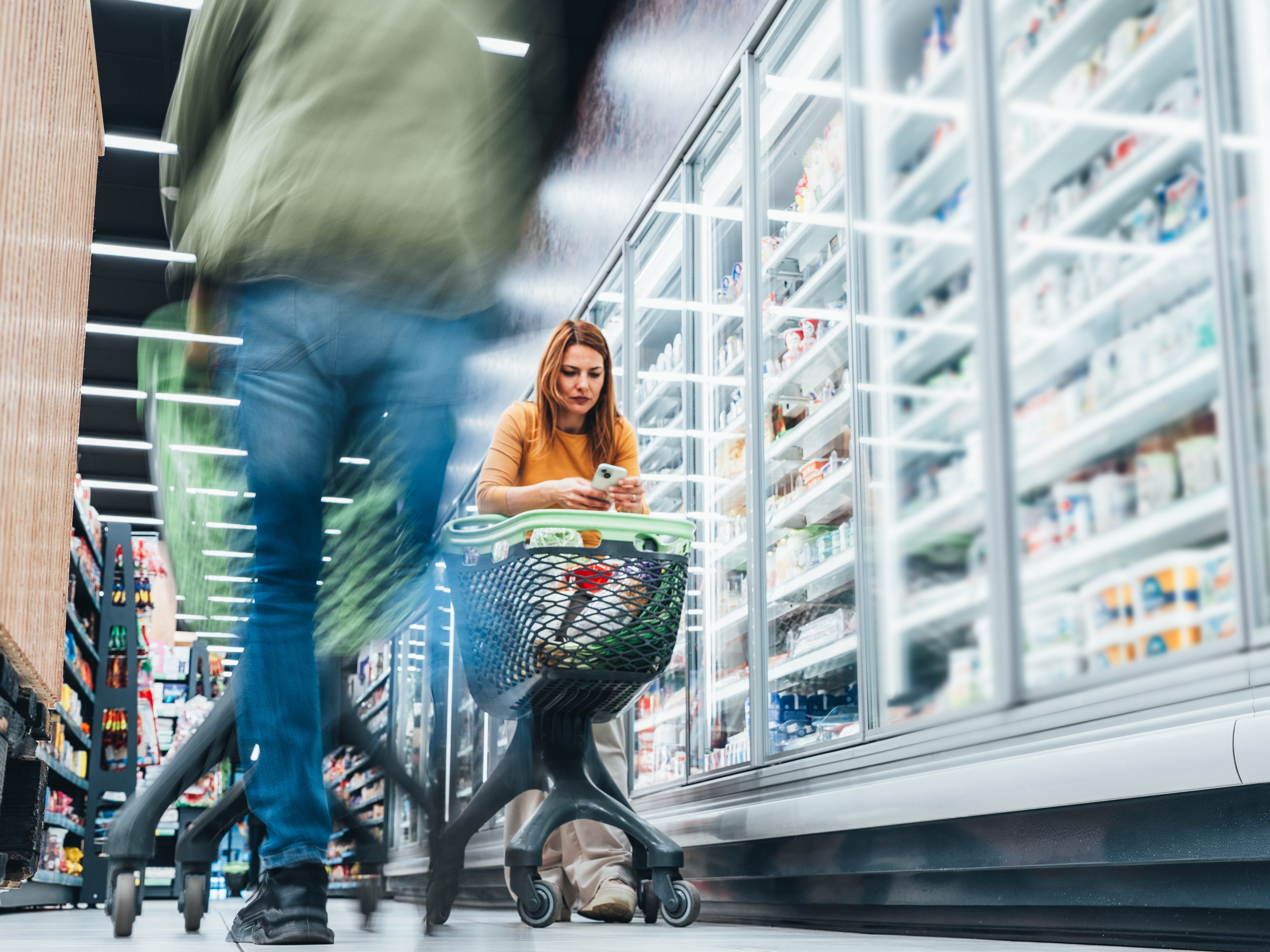 a woman on her phone while grocery shopping