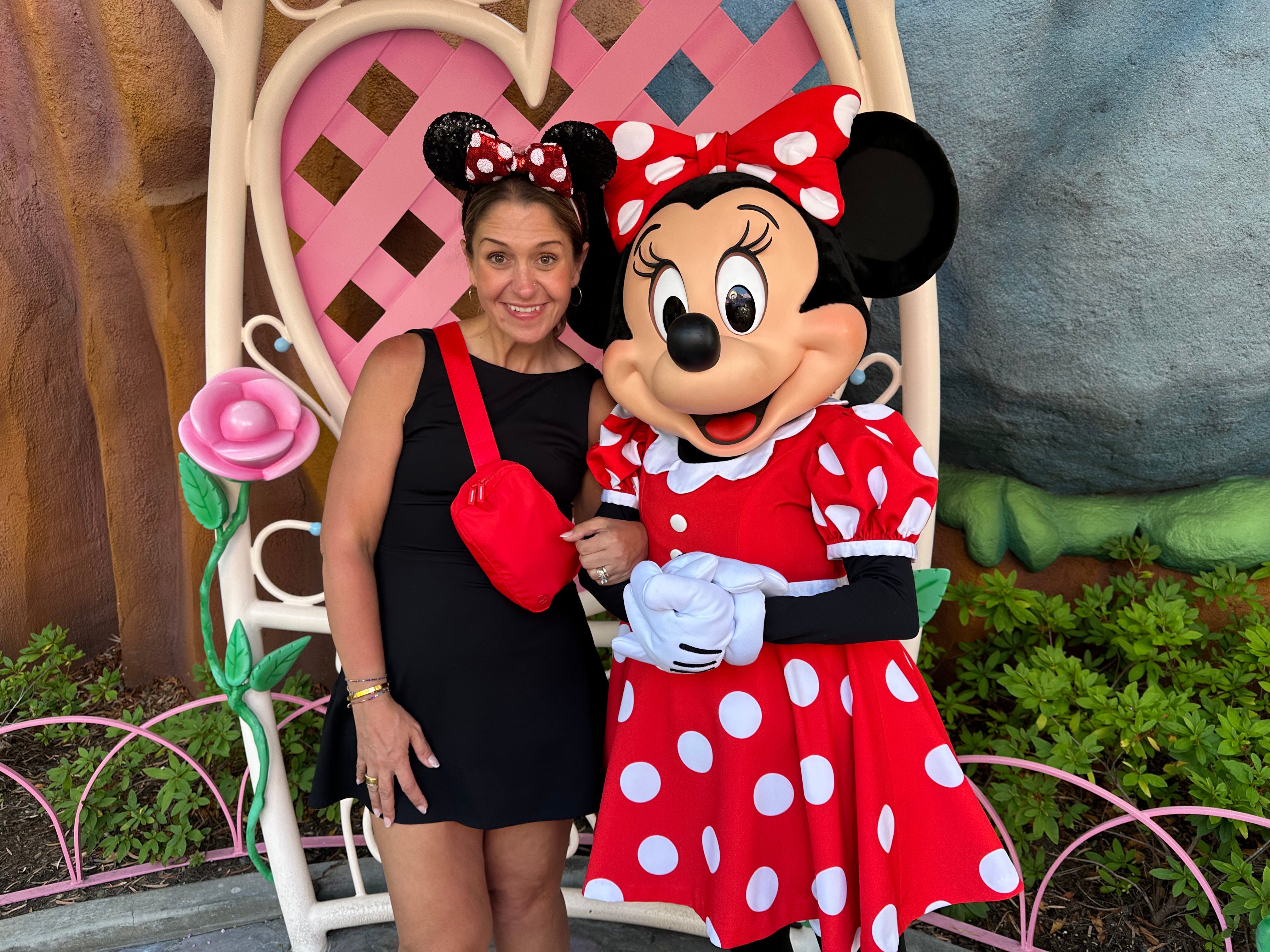The author wearing Minnie Mouse ears and posing for a picture with Minnie Mouse.