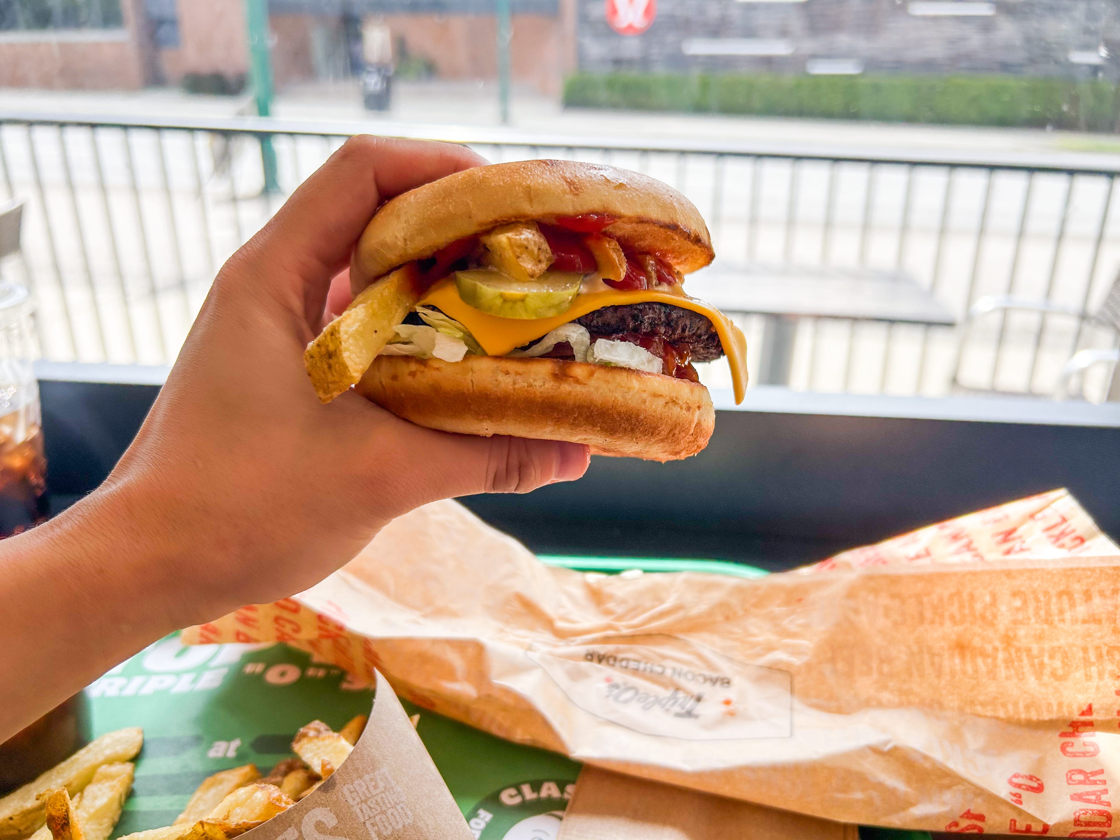 A hand holds a cheeseburger inside a Triple O's in Vancouver, British Columbia