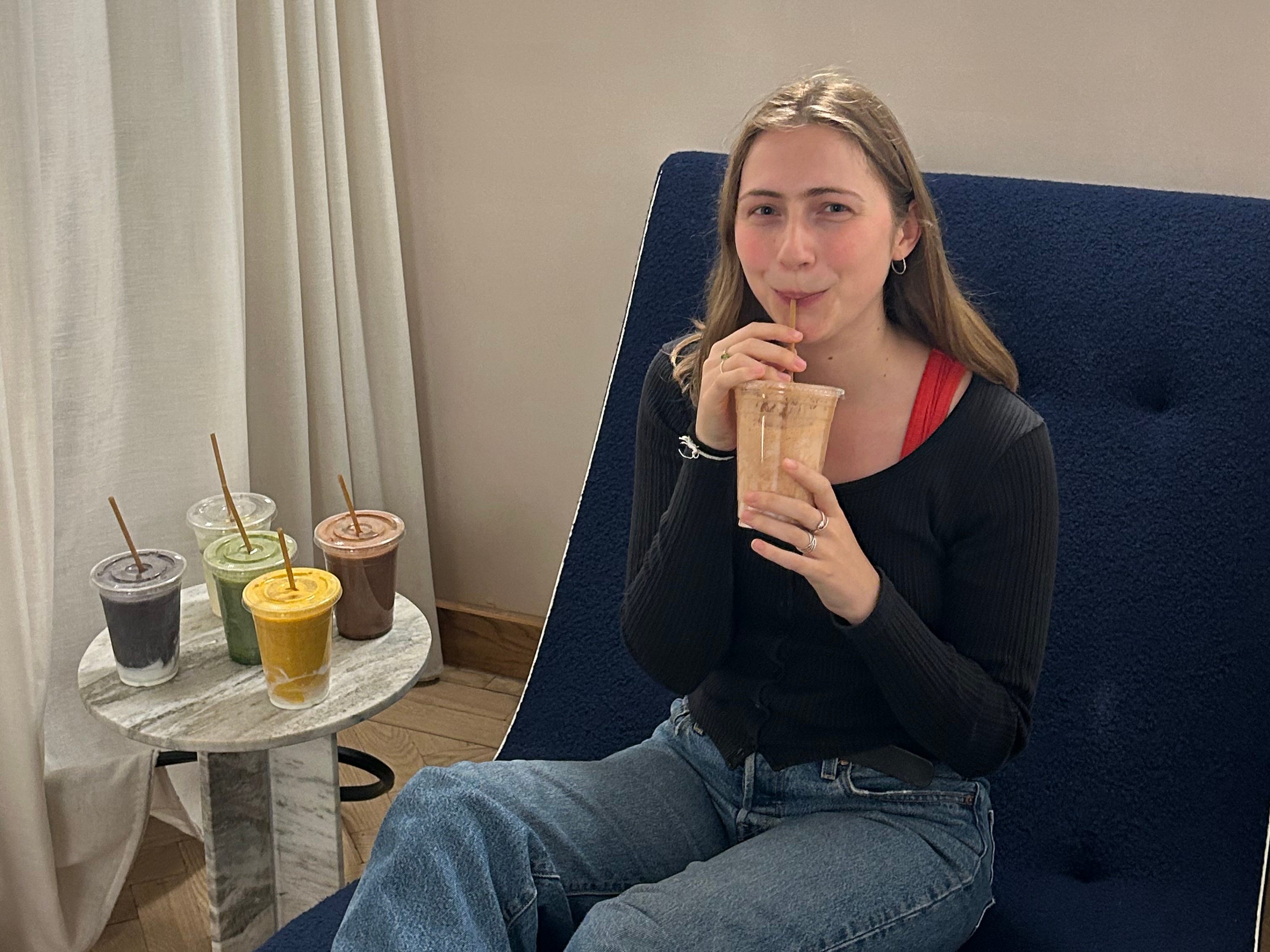 A woman sipping a smoothie.