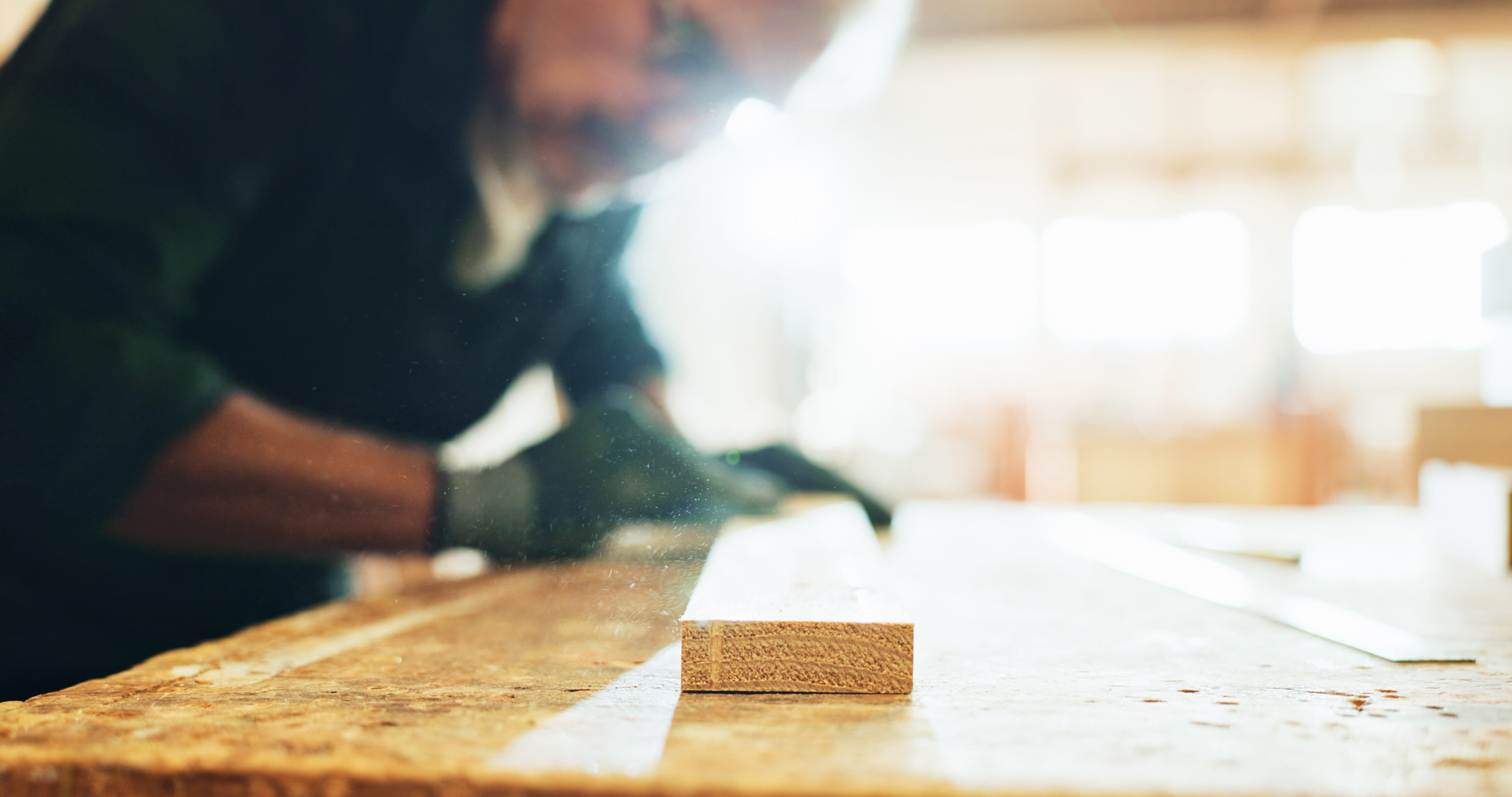 Carpenter, woodworking and man with sandpaper, polishing and smooth surface with tool and manufacturing. Production, artisan and person with gloves for safety, grip and shape of material in business