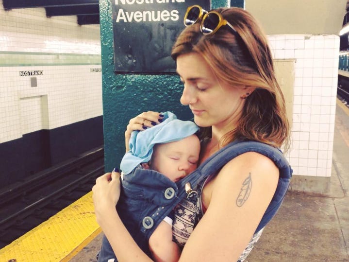 Woman with baby in carrier on her chest waiting for subway