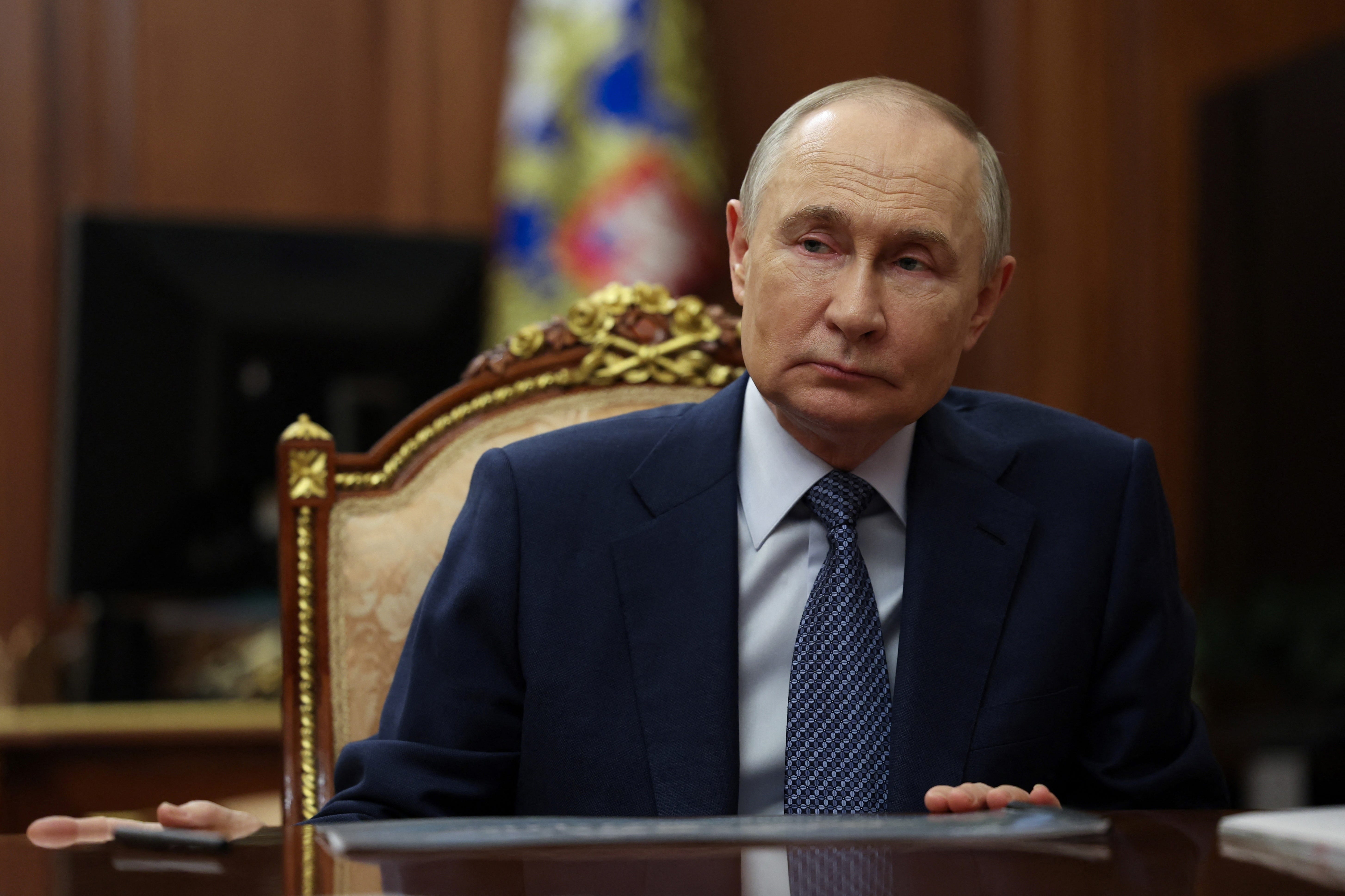 Russian President Vladimir Putin seated, looking to the side.