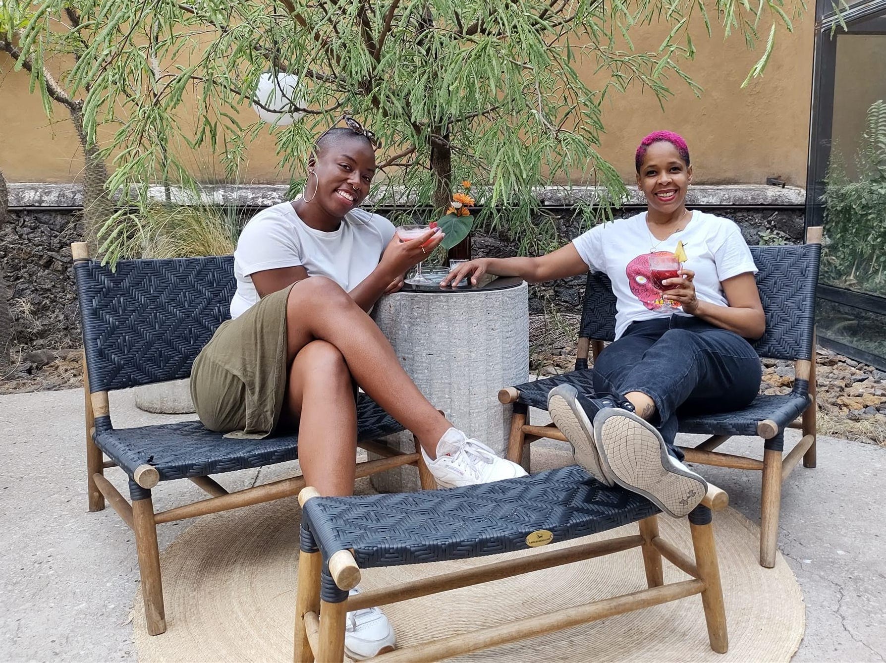 Author Ivana Robinson sitting on chairs with her roommate, both holding drinks
