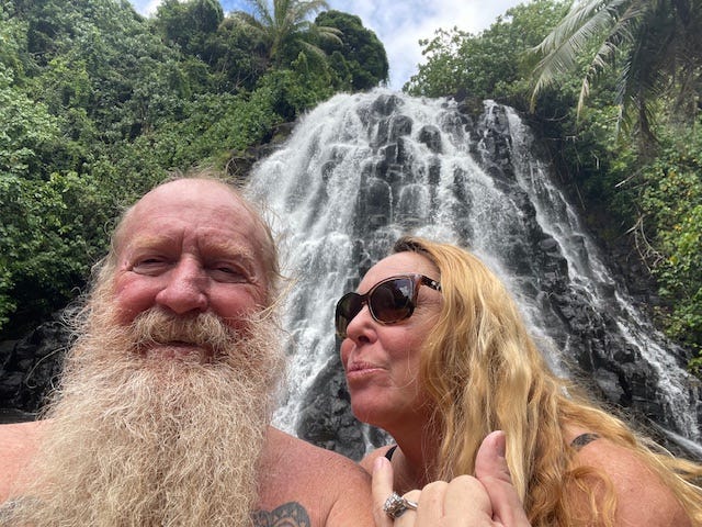 A couple taking a selfie in front of a waterfall.