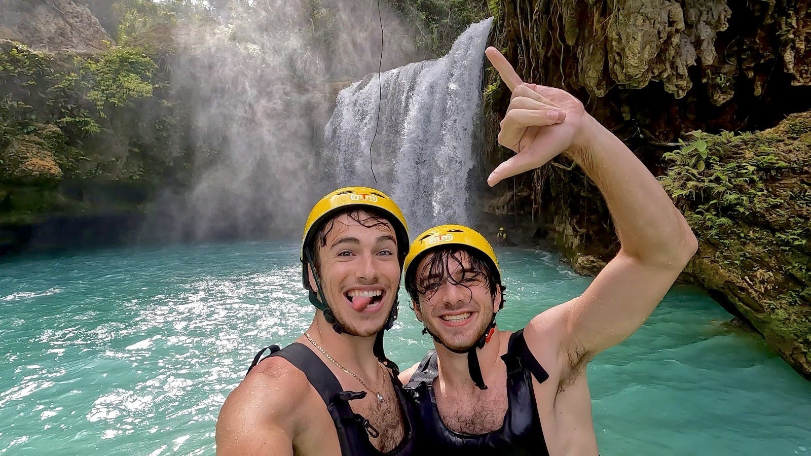 two men in helmets at a waterfall