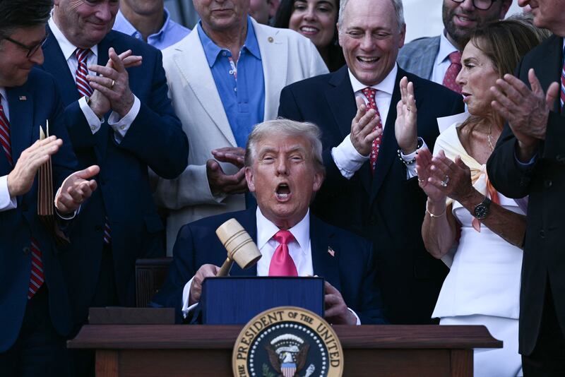 US President Donald Trump (C) holds a gavel after signing the "Big Beautiful Bill Act" at the White House in Washington, DC, on July 4, 2025. US President Donald Trump signed his flagship tax and spending bill on July 4 in a pomp-laden Independence Day ceremony featuring fireworks and a flypast by the type of stealth bomber that bombed Iran. Trump pushed Republican lawmakers to get his unpopular "One Big Beautiful Bill" through a reluctant Congress in time for him to sign it into law on the US national holiday -- and they did so with a day to spare Thursday. (Photo by Brendan SMIALOWSKI / POOL / AFP) (Photo by BRENDAN SMIALOWSKI/POOL/AFP via Getty Images)