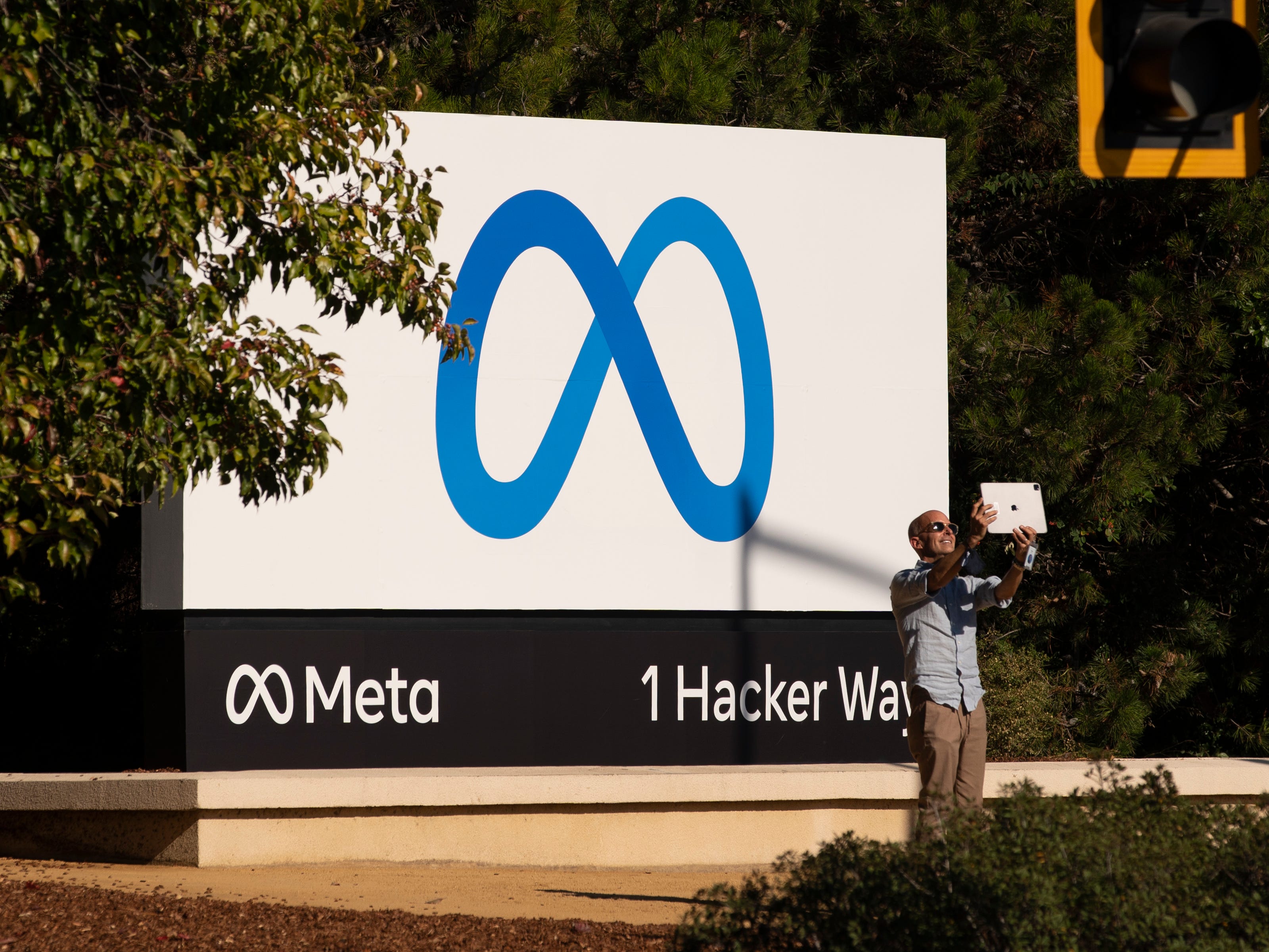 A man takes pictures in front of a sign showing logo of Meta outside Facebook headquarters on October 28, 2021 in Menlo Park, California.