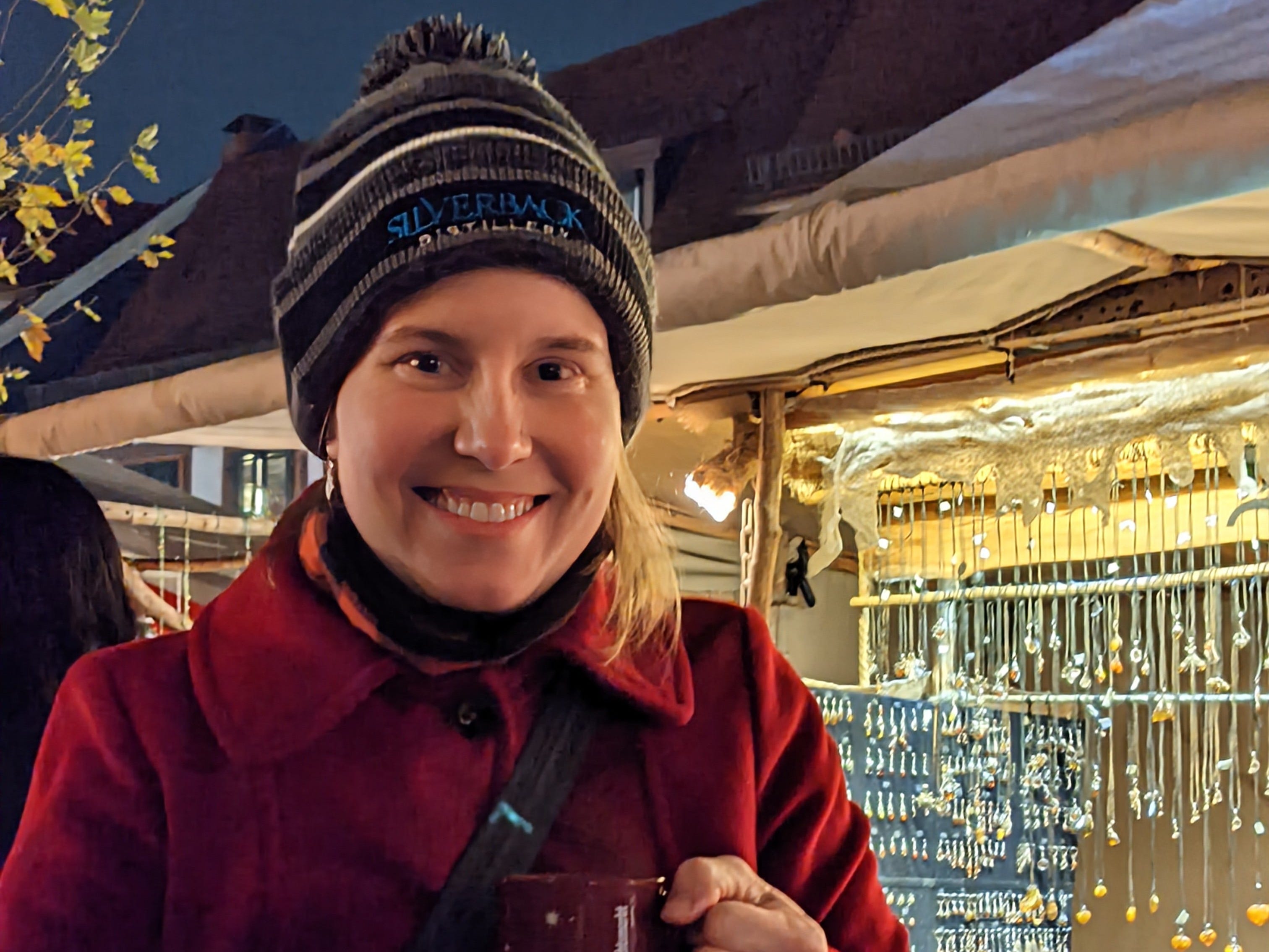 A woman wearing a winter cap while enjoying at hot drink at a Christmas market in Germany.