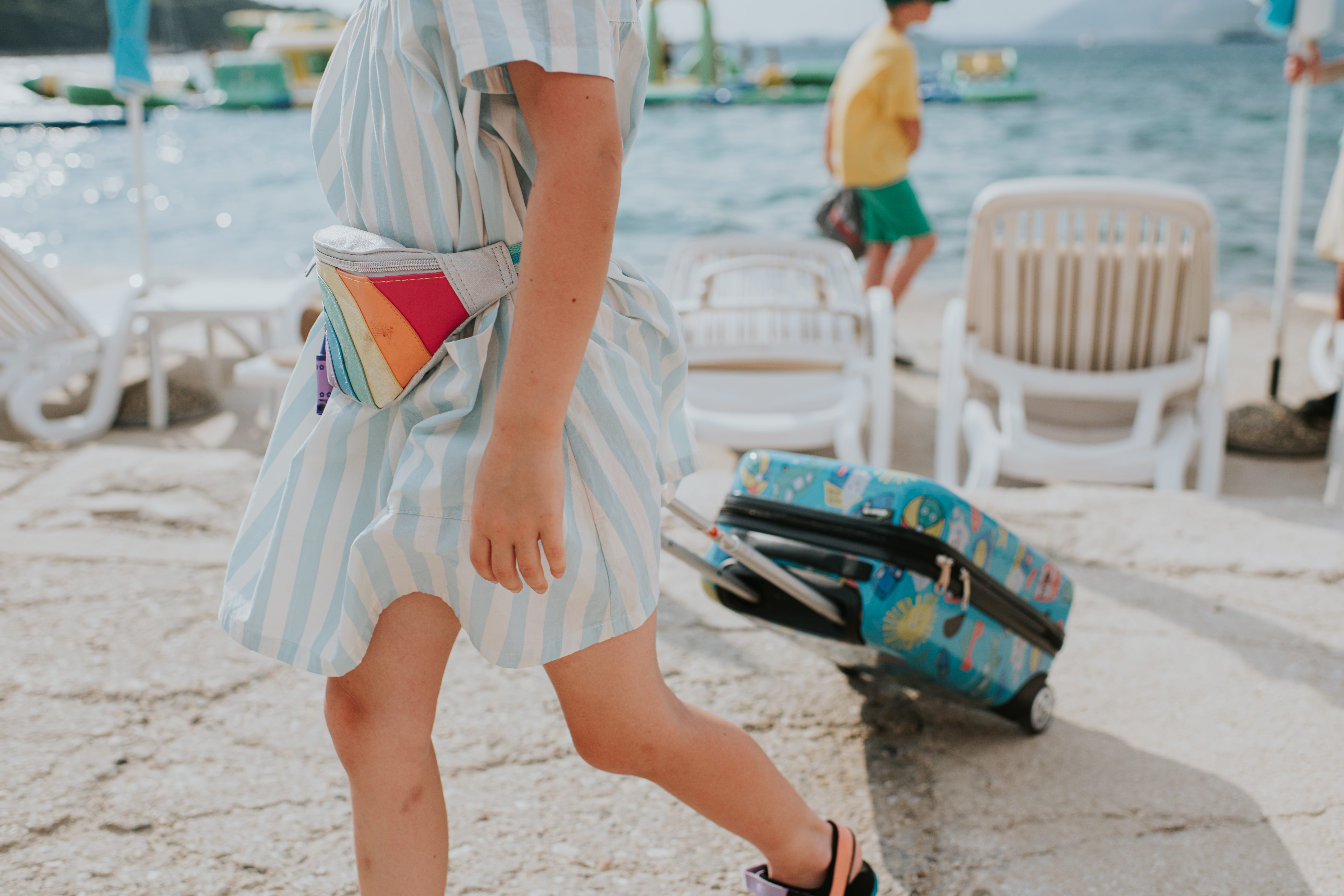 A little girl pulls along wheeled luggage in a tourist resort