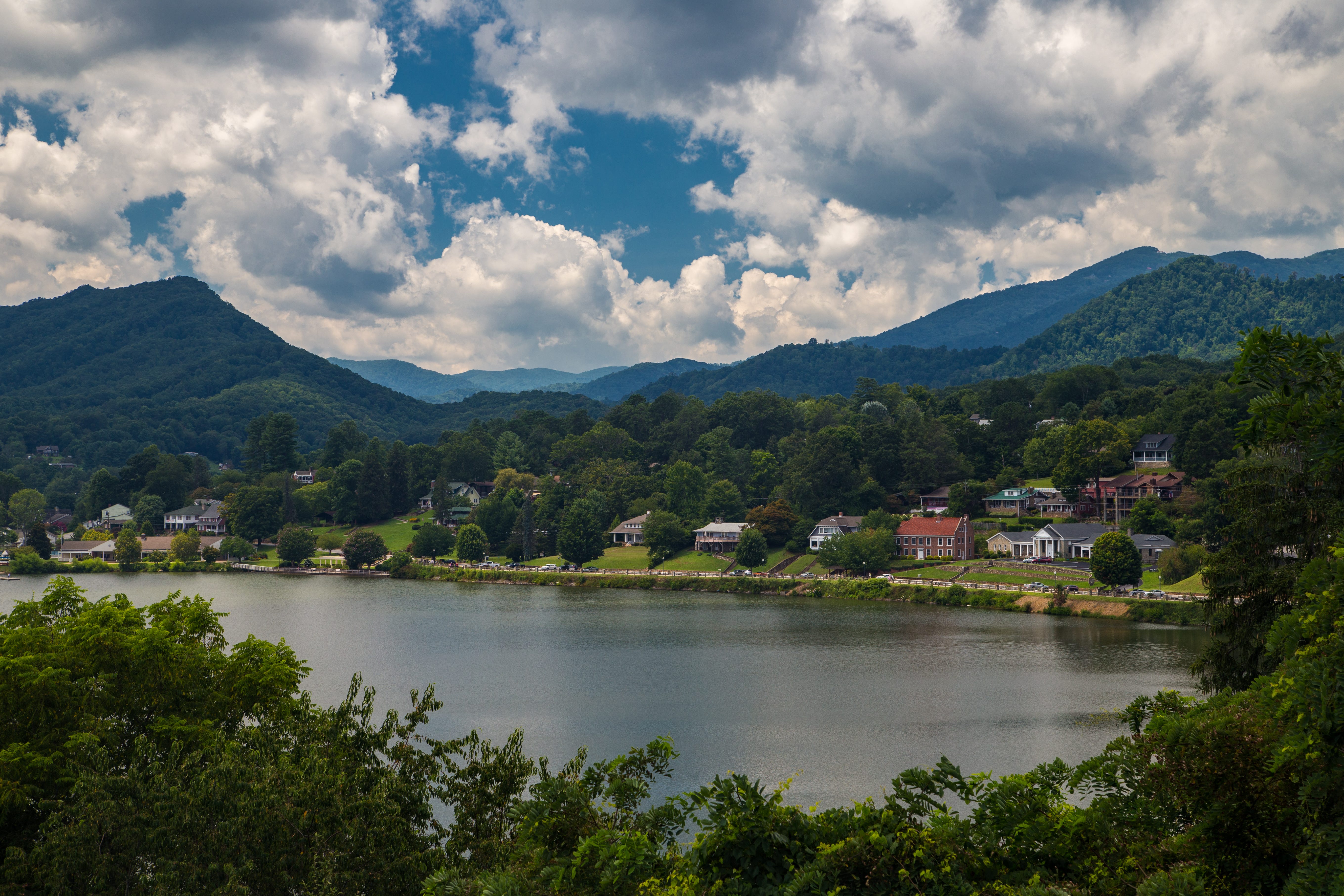 View of hosues along waterfront in front of trees, mountains in MAggie Valley