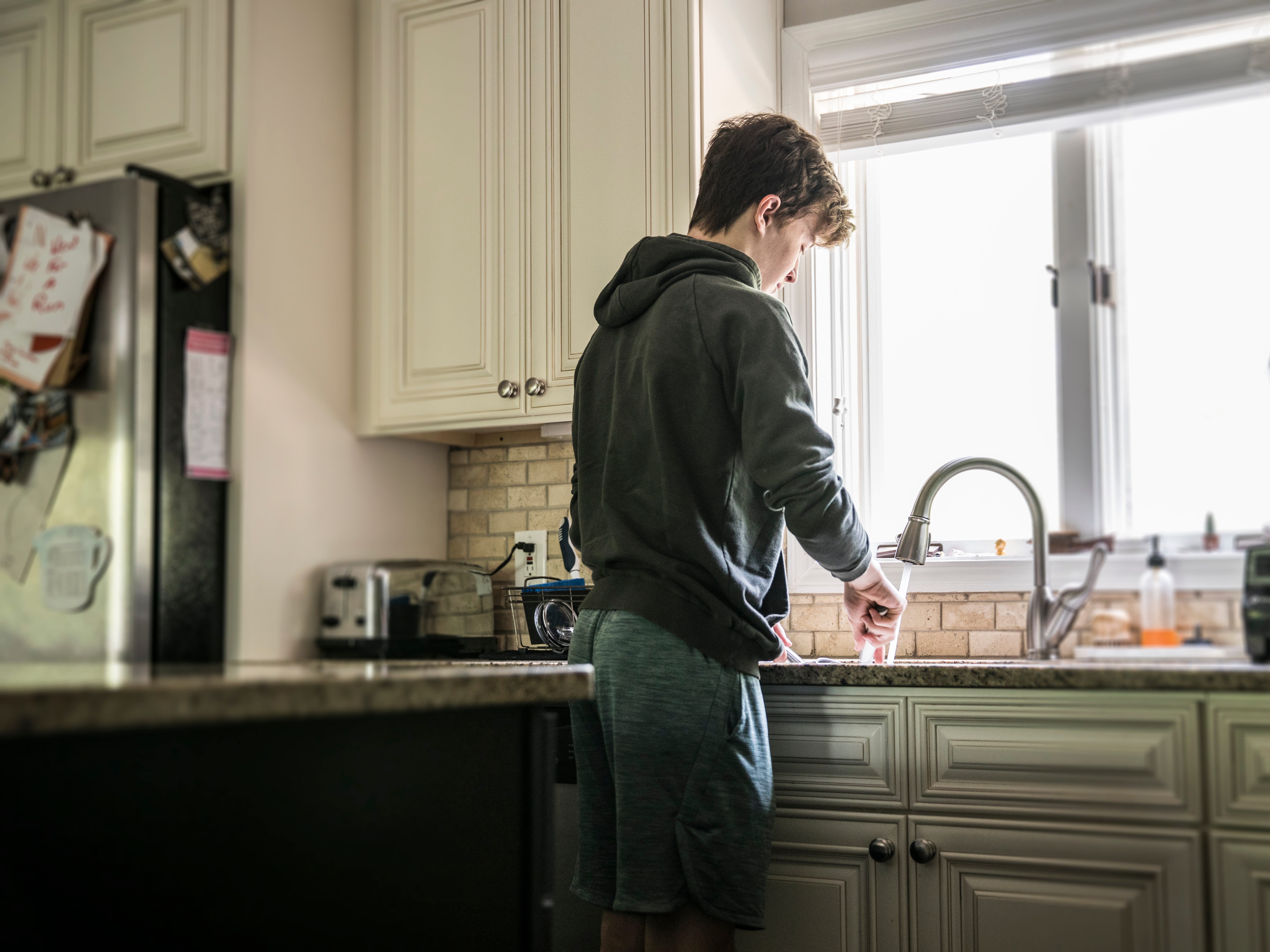 a teenage boy washing dishes