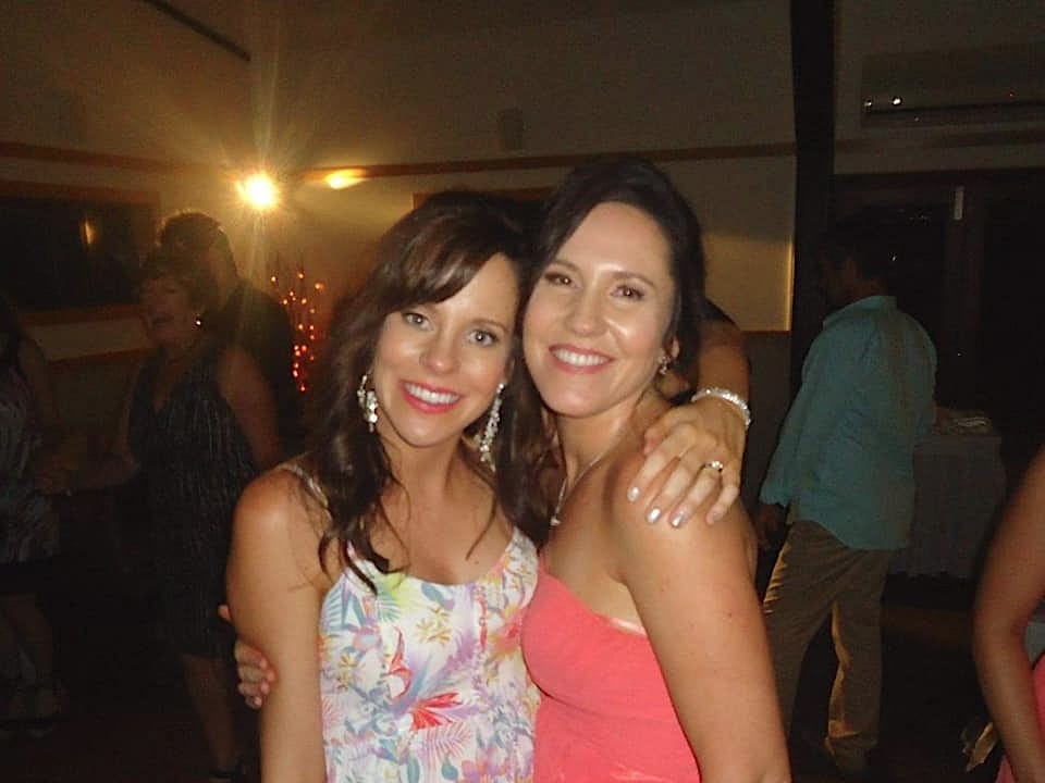 The author and her sister wearing colorful dresses and smiling at the camera.