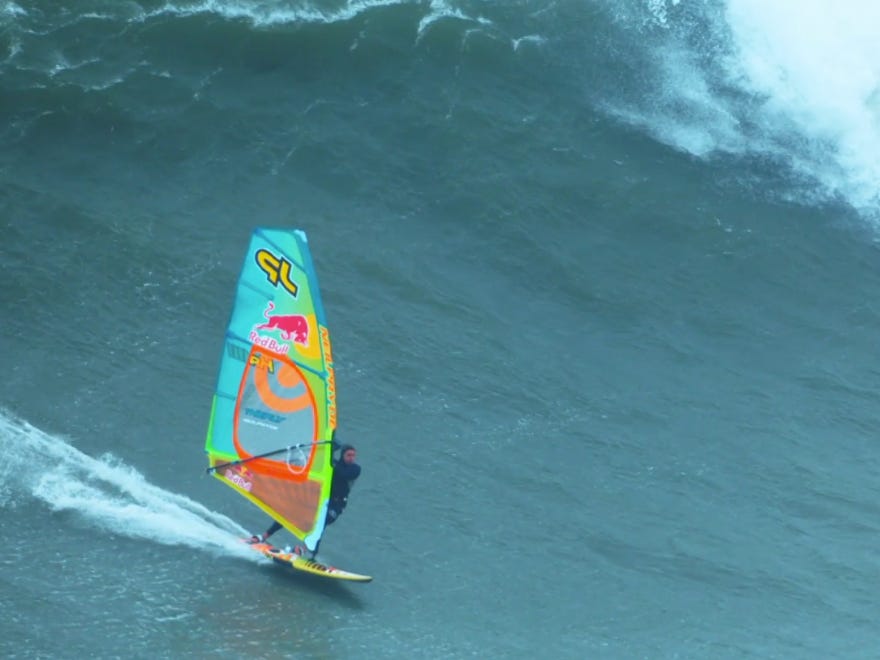 A windsurfer rides a giant wave