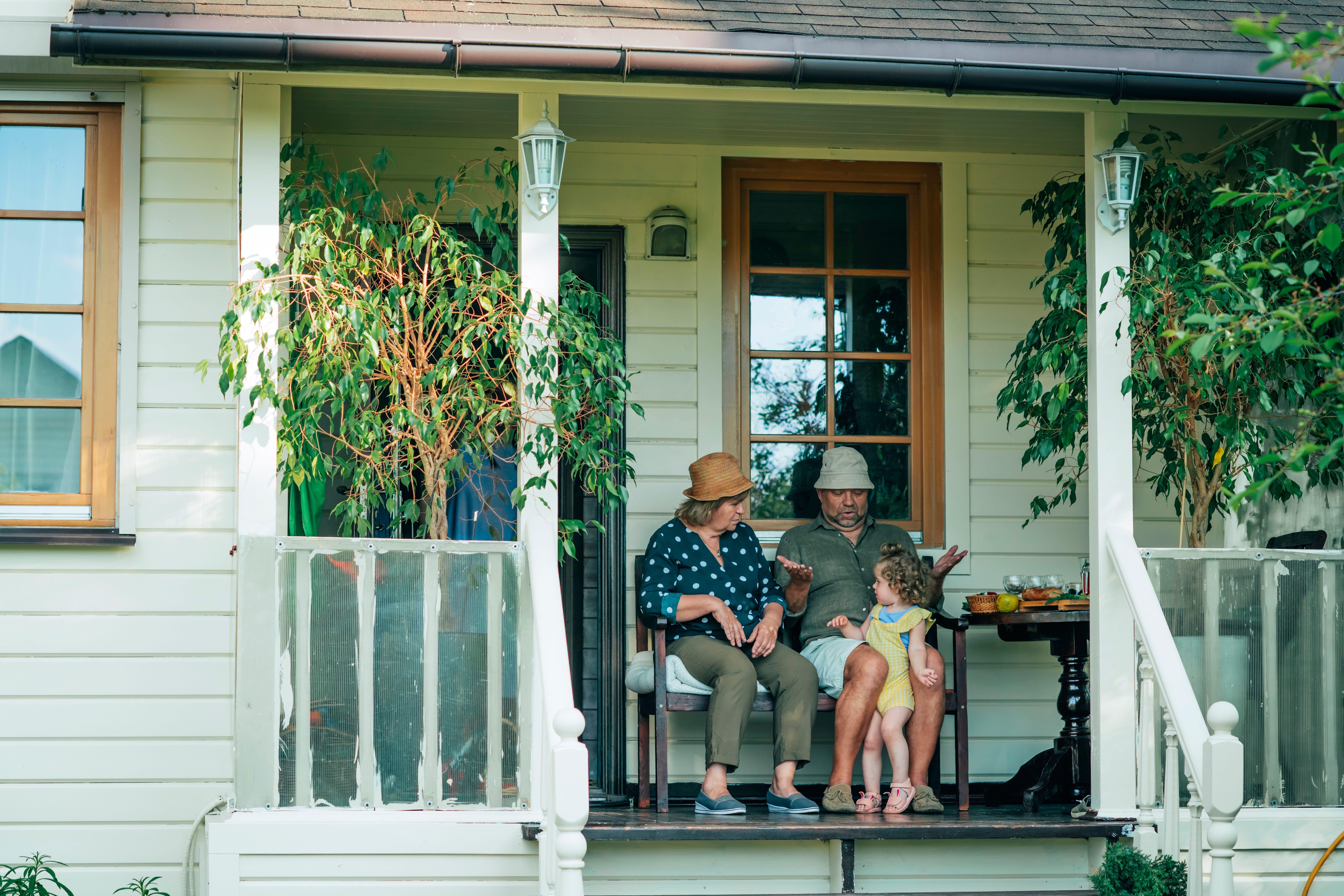 An older couple playing with a young child on a porch.