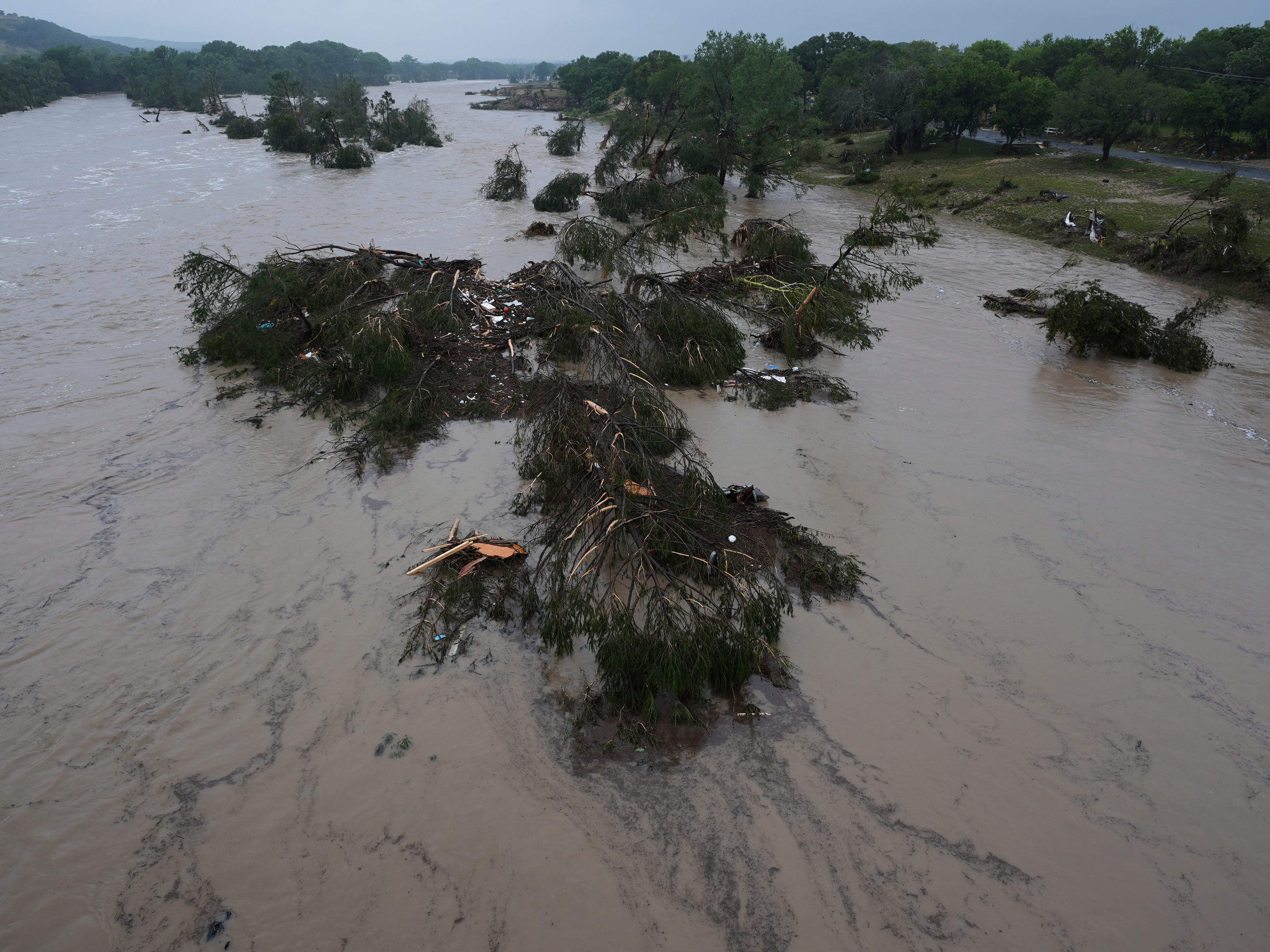 A raging Guadalupe River leaves fallen trees and debris in its wake, Friday, July 4, in Kerrville, Texas.