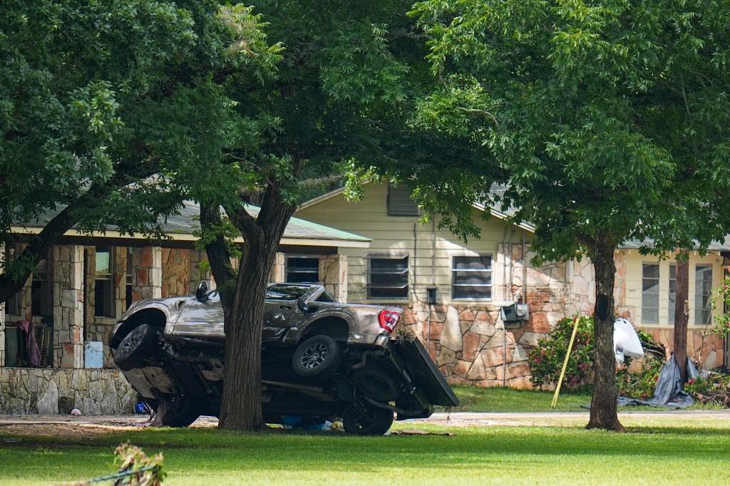 Truck resting on its side in a tree after a flash flood.