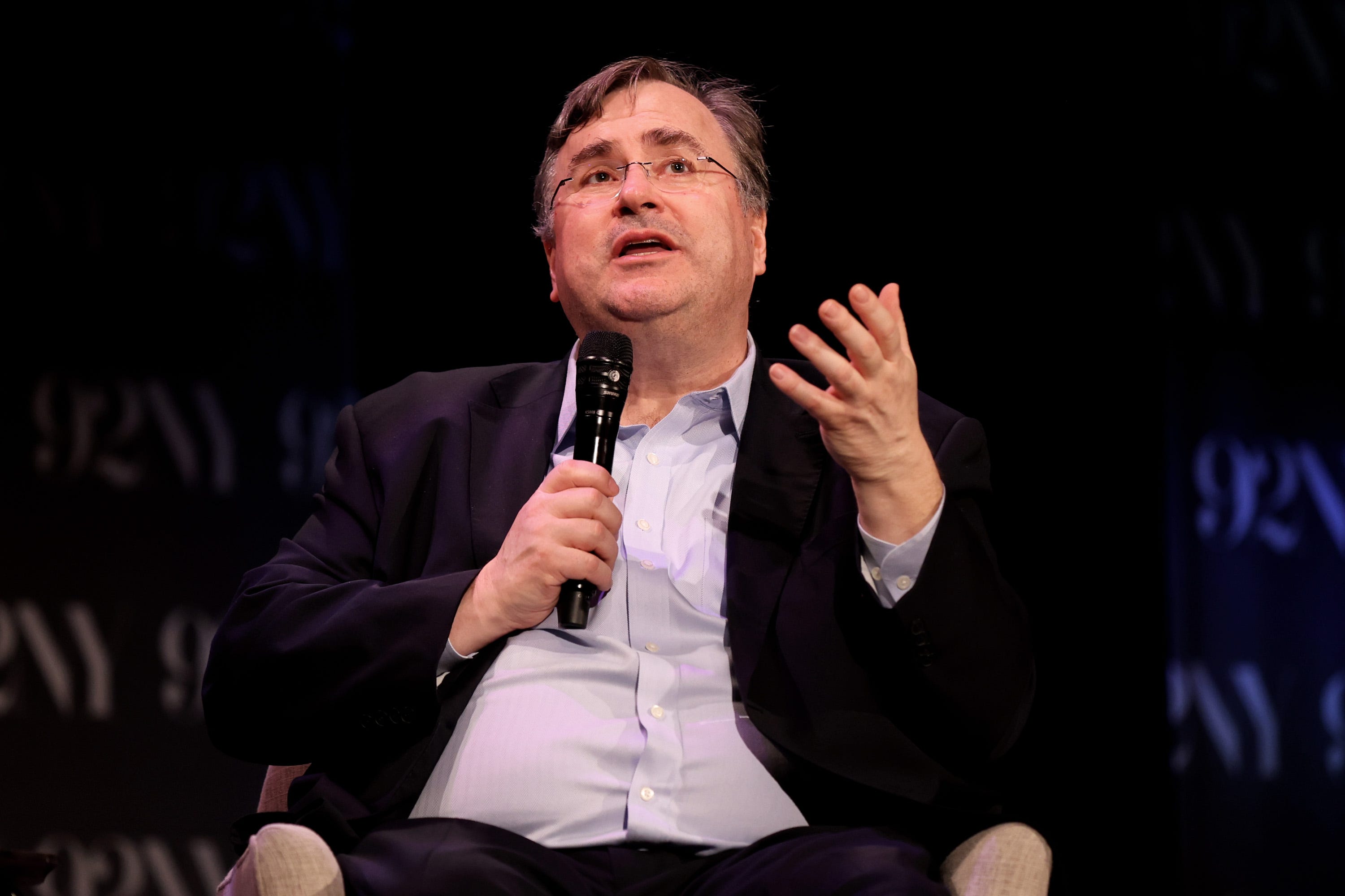 Reid Hoffman speaking to a microphone while seated.