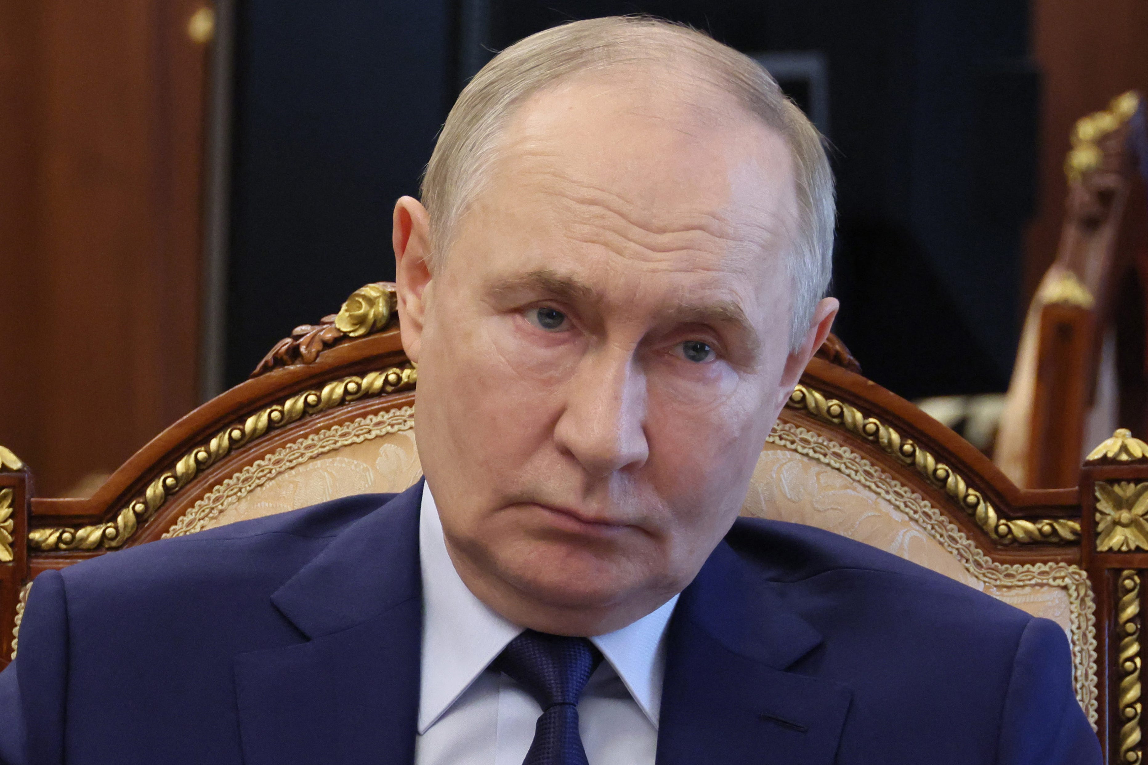 Russian President Vladimir Putin shoulder up sitting on a chair