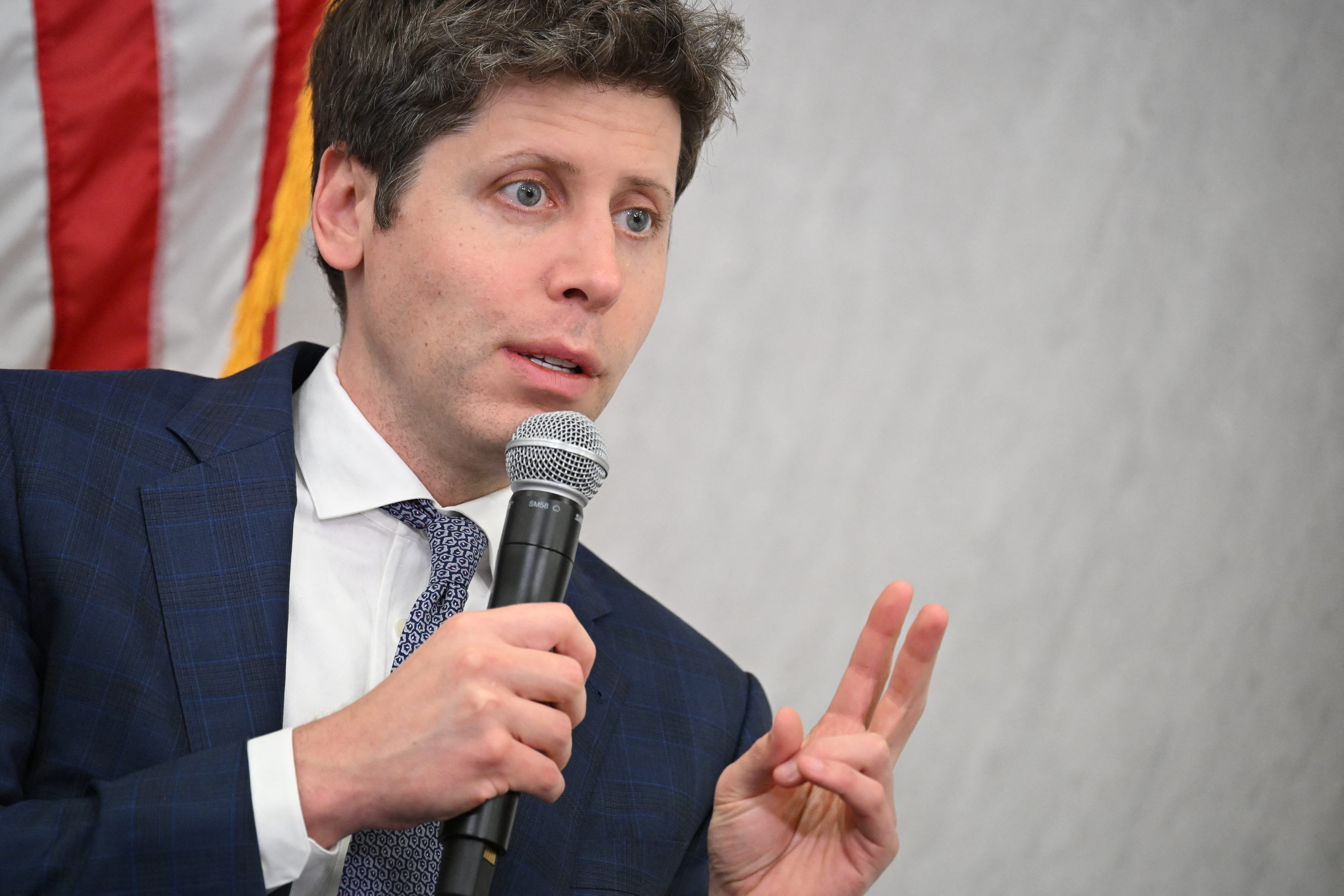 Sam Altman holding a microphone and speaking.