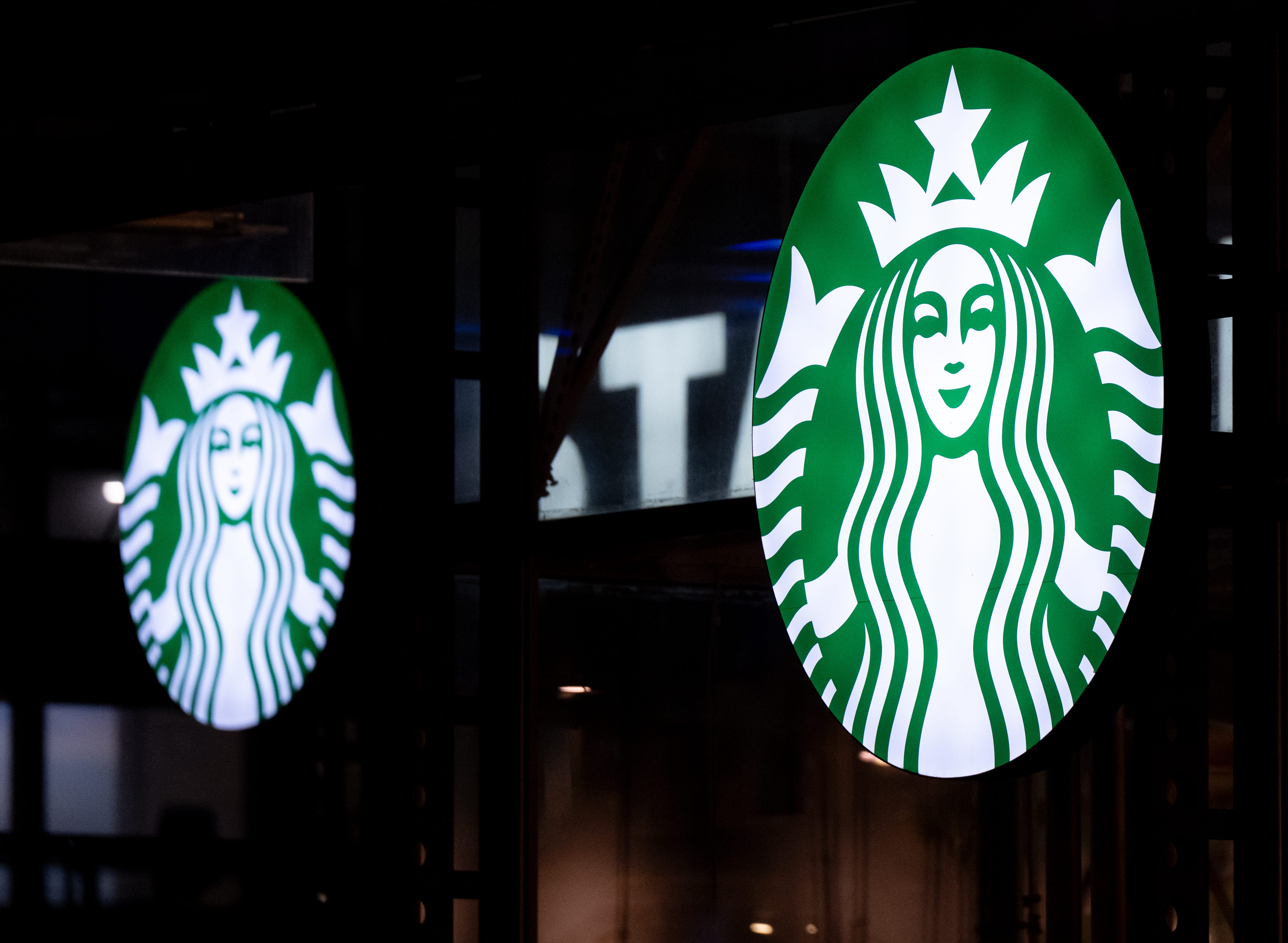 The Starbucks logo is seen on a dark background.