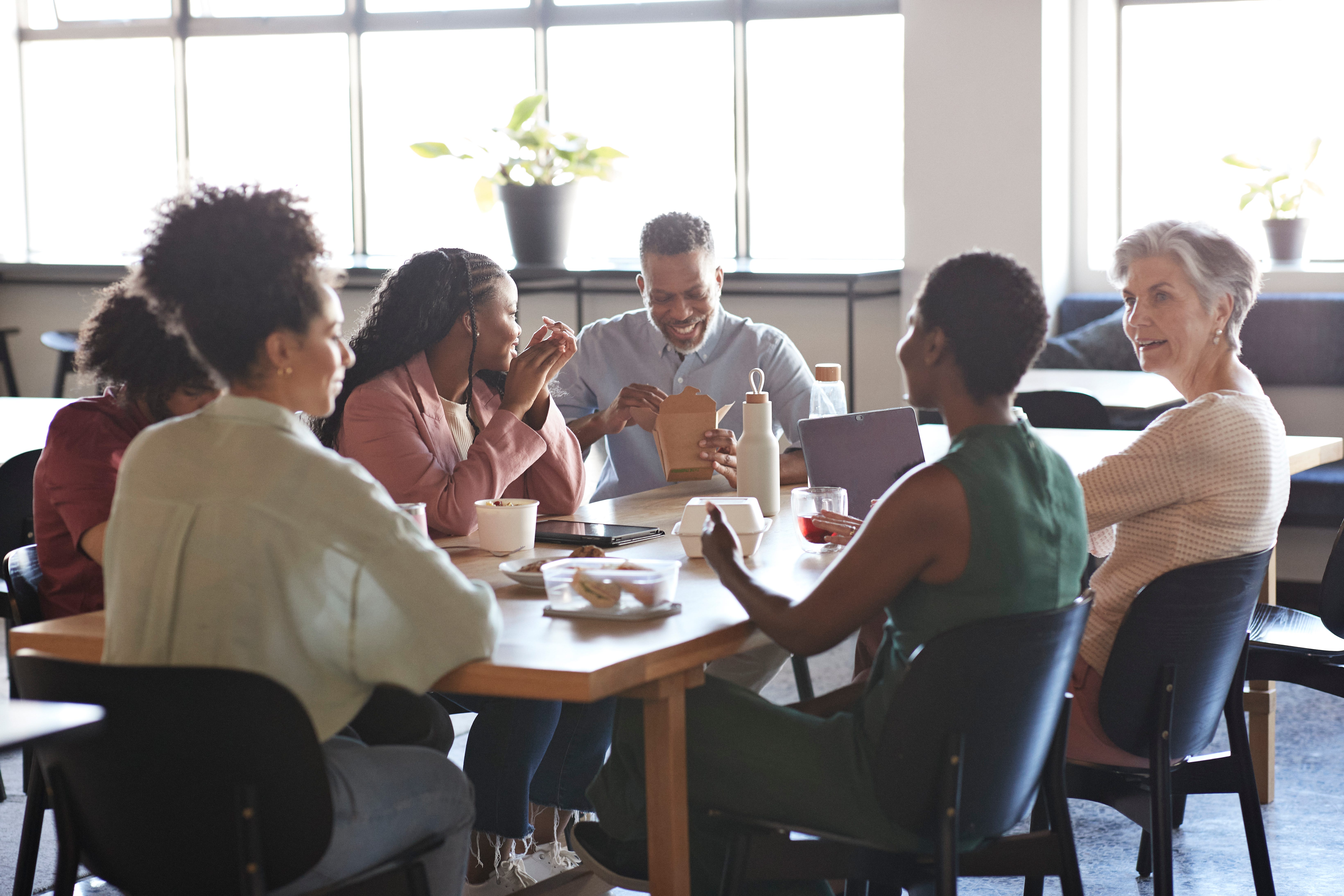 Office workers eat lunch around a table