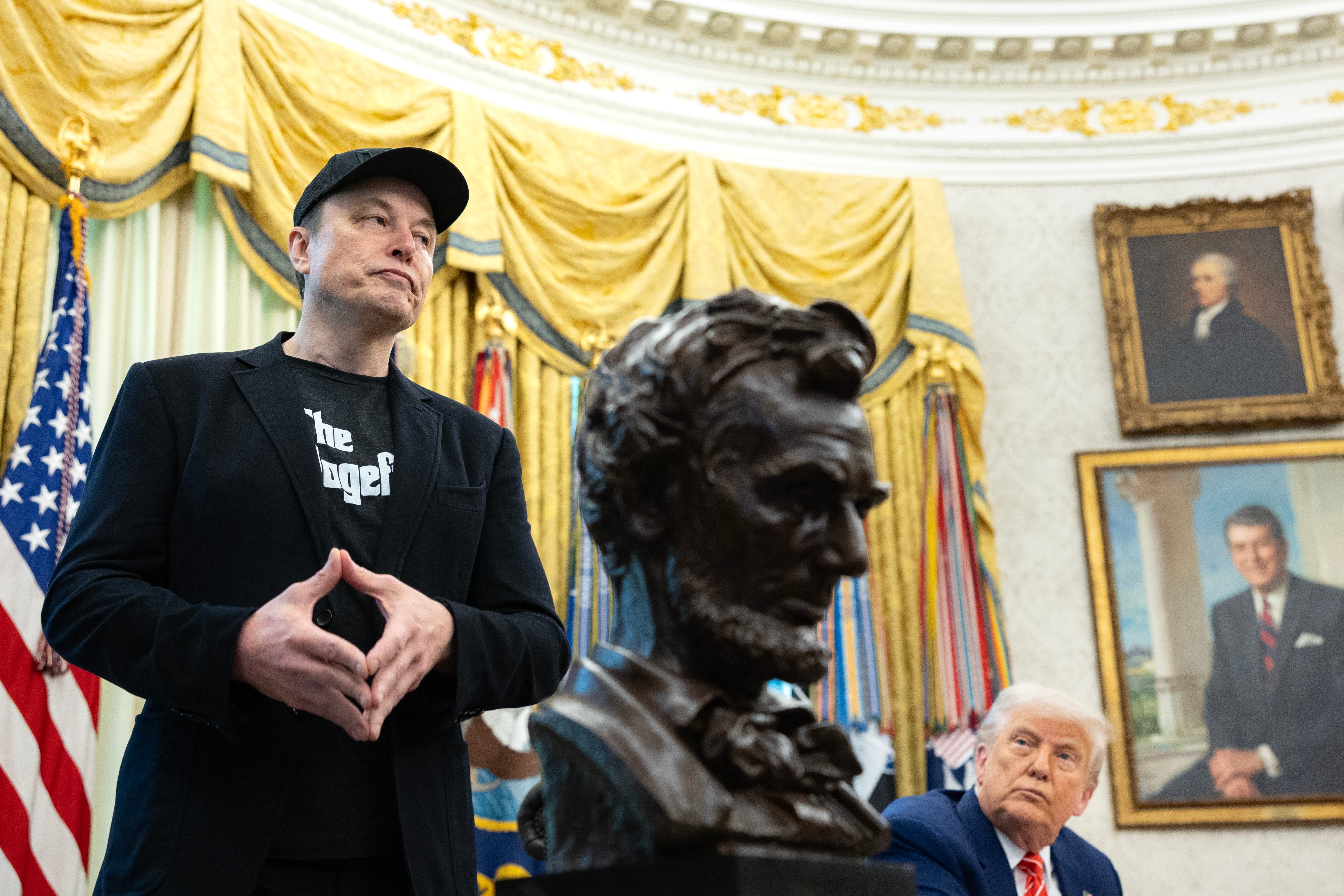 The Oval Office with Donald Trump seated, Elon Musk standing an a bust of Abraham Lincolin in the foreground