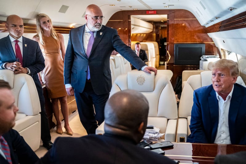 Chris LaCivita, center, listens as former President Donald Trump speaks with reporters on Trump Force One.