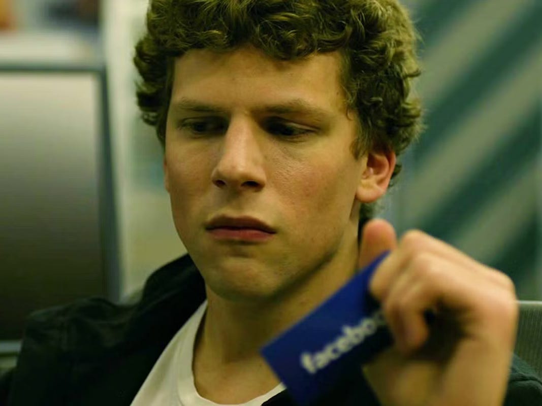 Jesse Eisenberg holding a Facebook card