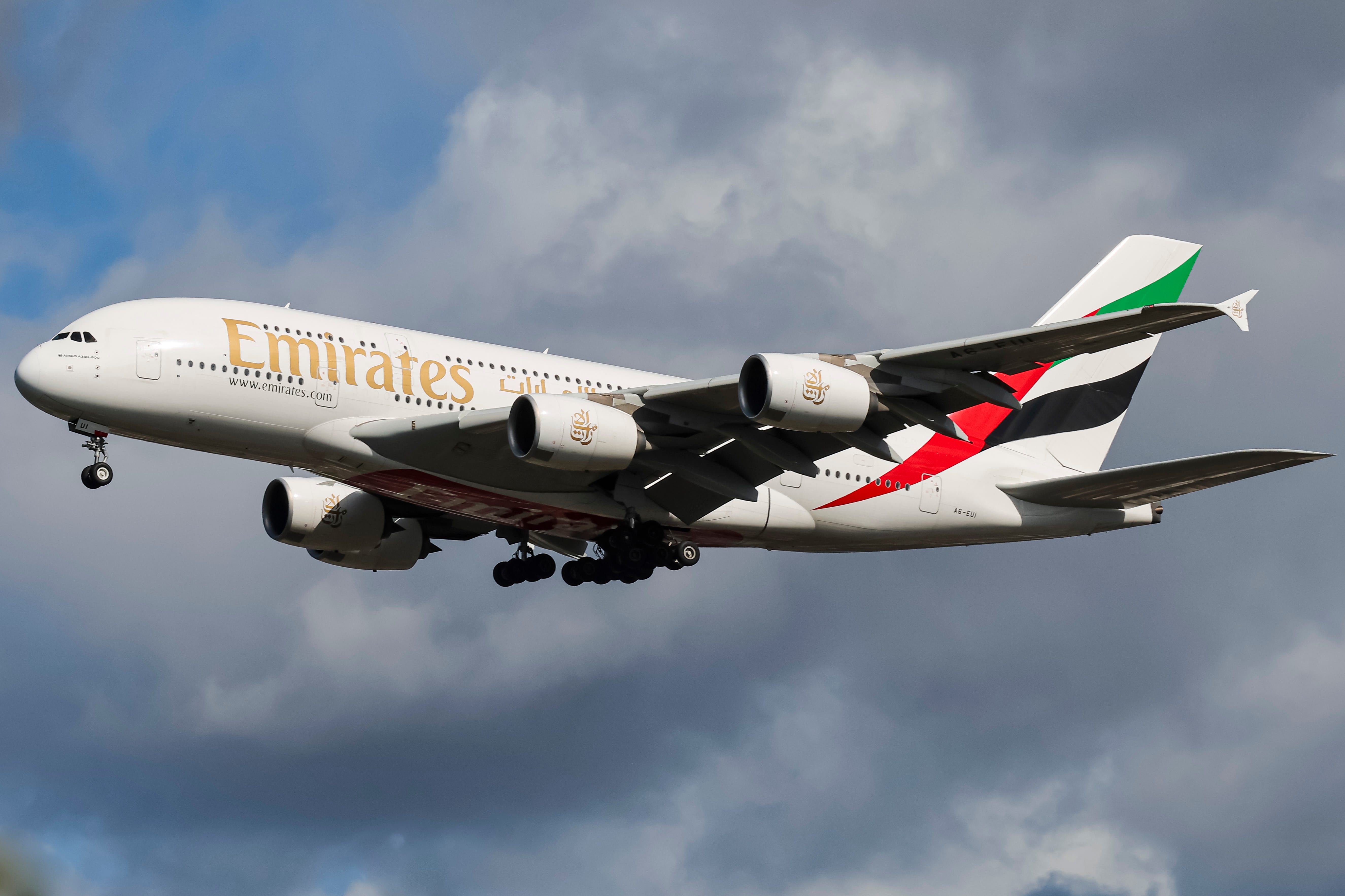 Emirates Airbus A380 double decker passenger aircraft spotted flying in the air between the blue sky and the clouds, on final approach for landing on the runway of London Heathrow Airport LHR
